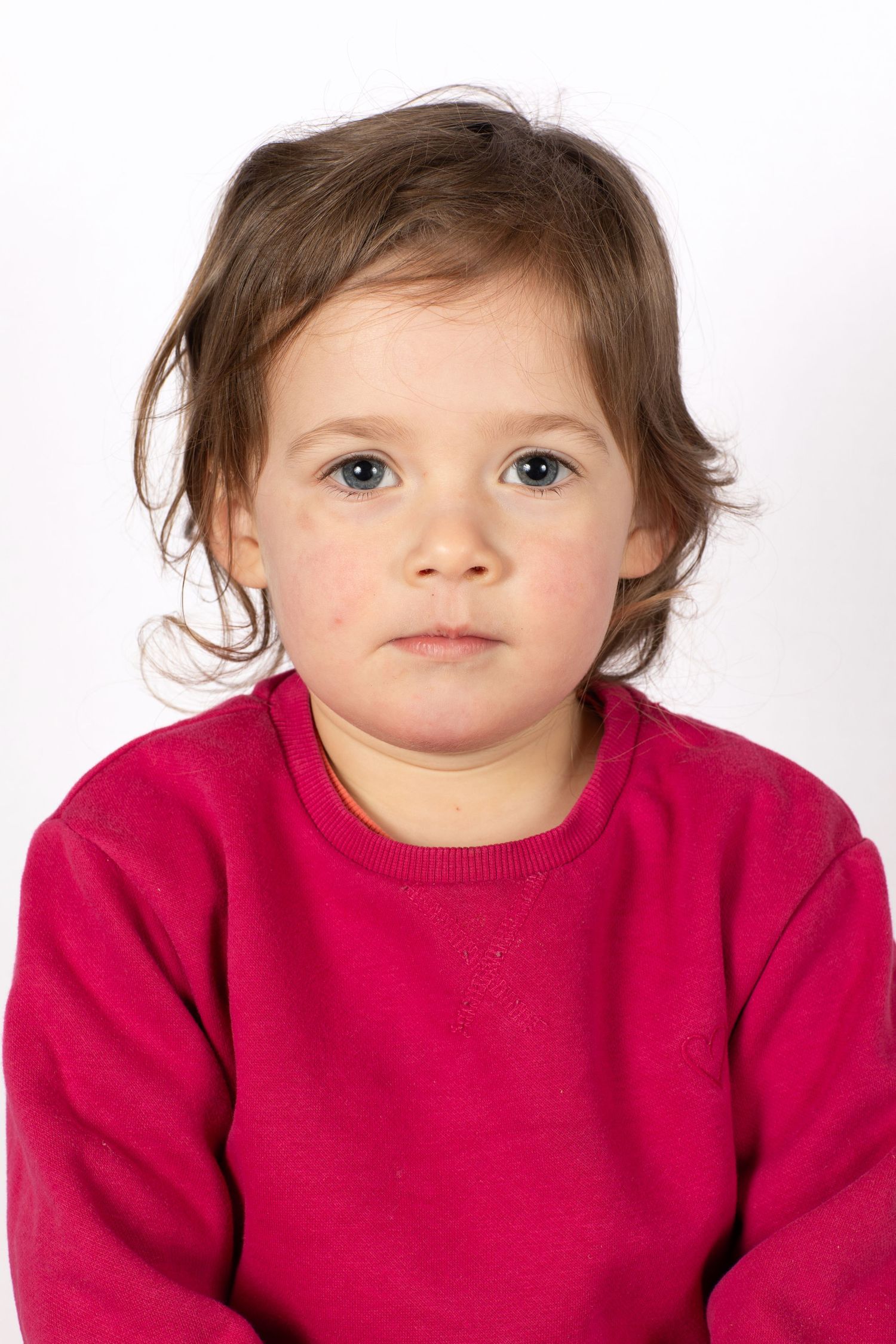 Child wearing bright red sweater in close-up portrait against white background.