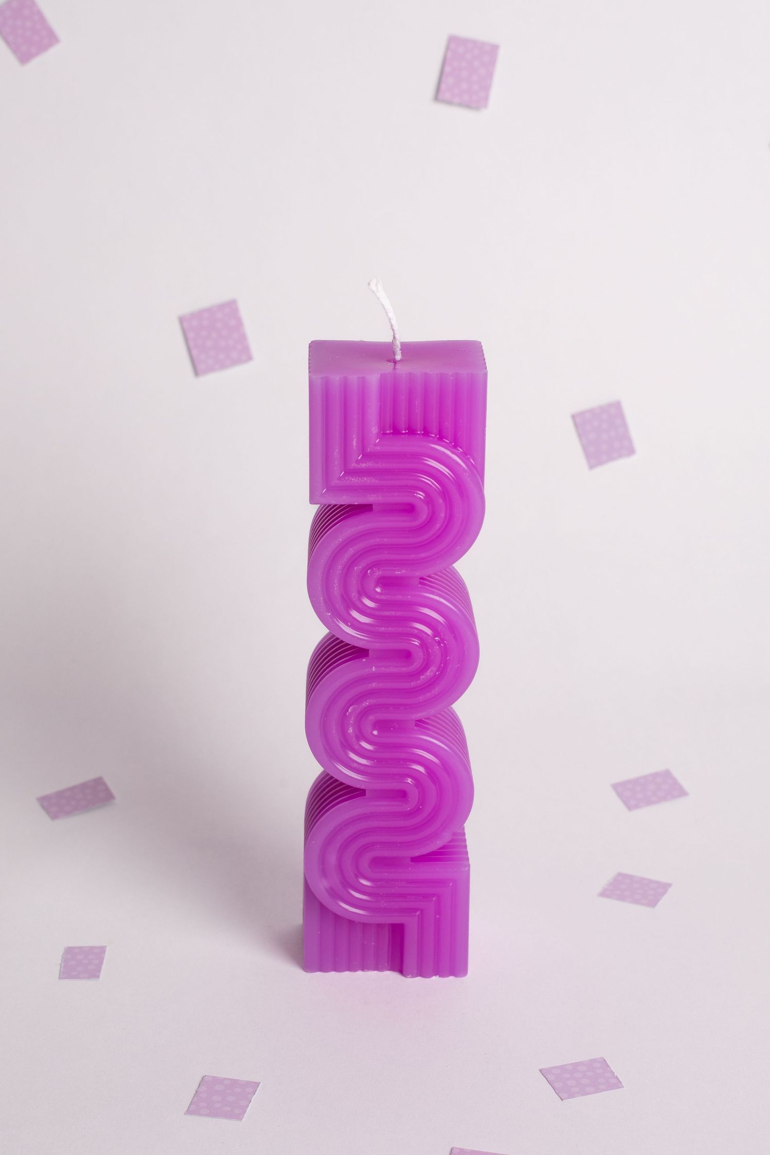 Purple zigzag-patterned decorative candle with scattered purple paper squares.