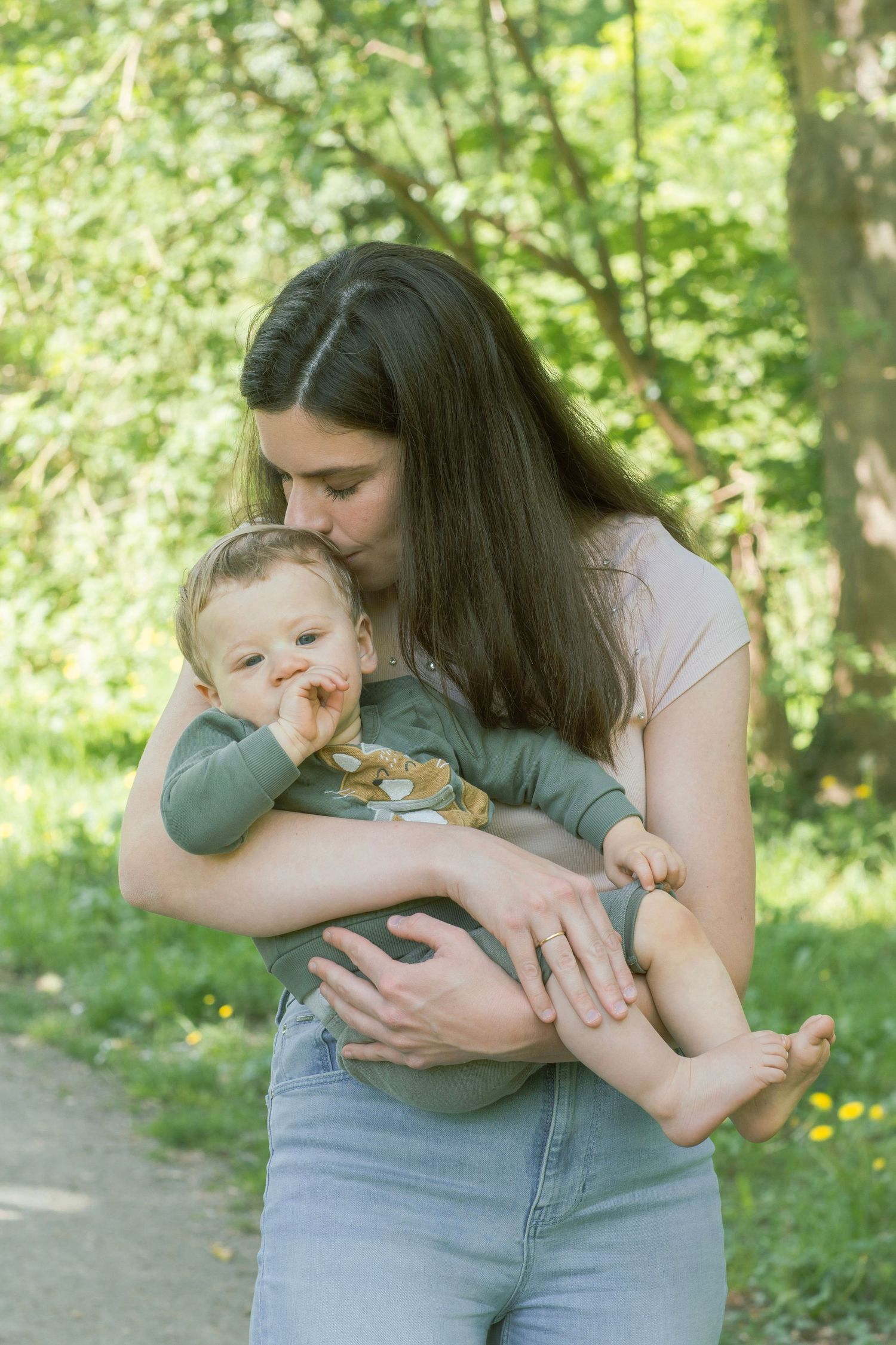Tender moments captured between parent and infant in a sunny garden setting.