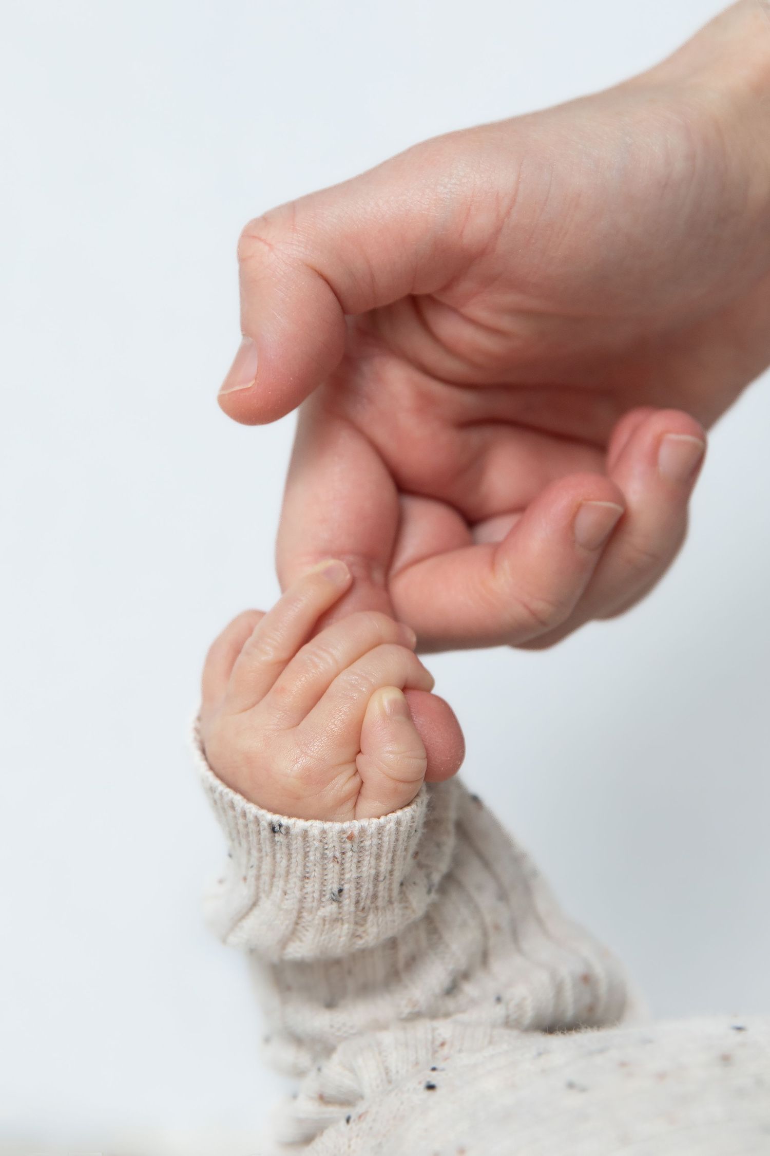 Hand pinching and pulling a soft knit fabric to demonstrate its stretchy elastic texture against a white background.