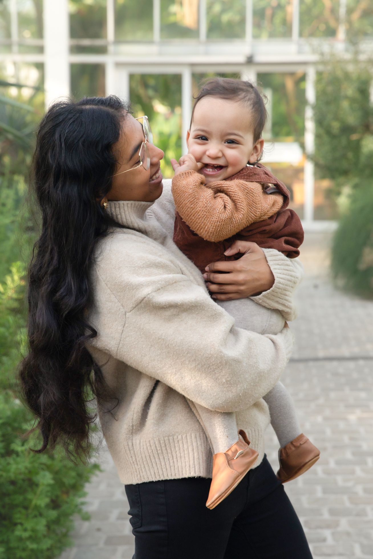 A sequence of tender moments between parent and child playing outdoors in warm sweaters on a sunny day.