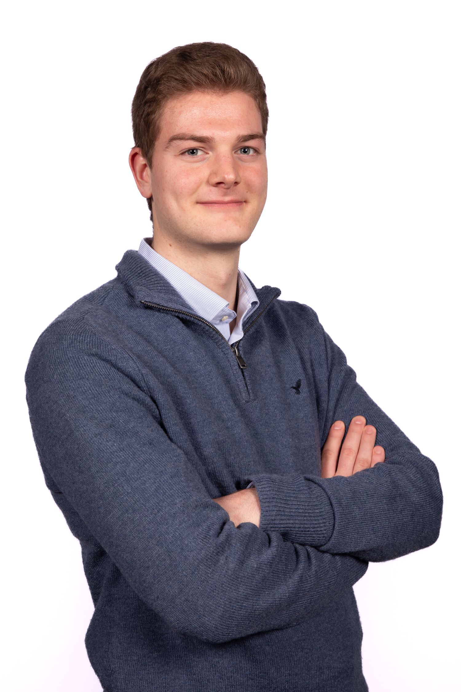 Professional headshot of someone in a gray quarter-zip sweater with arms crossed, against white background.