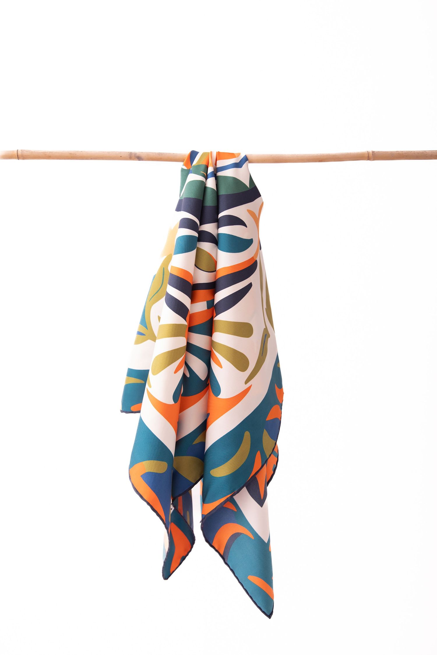 Colorful abstract geometric pattern silk scarves hanging on display rods against white background.