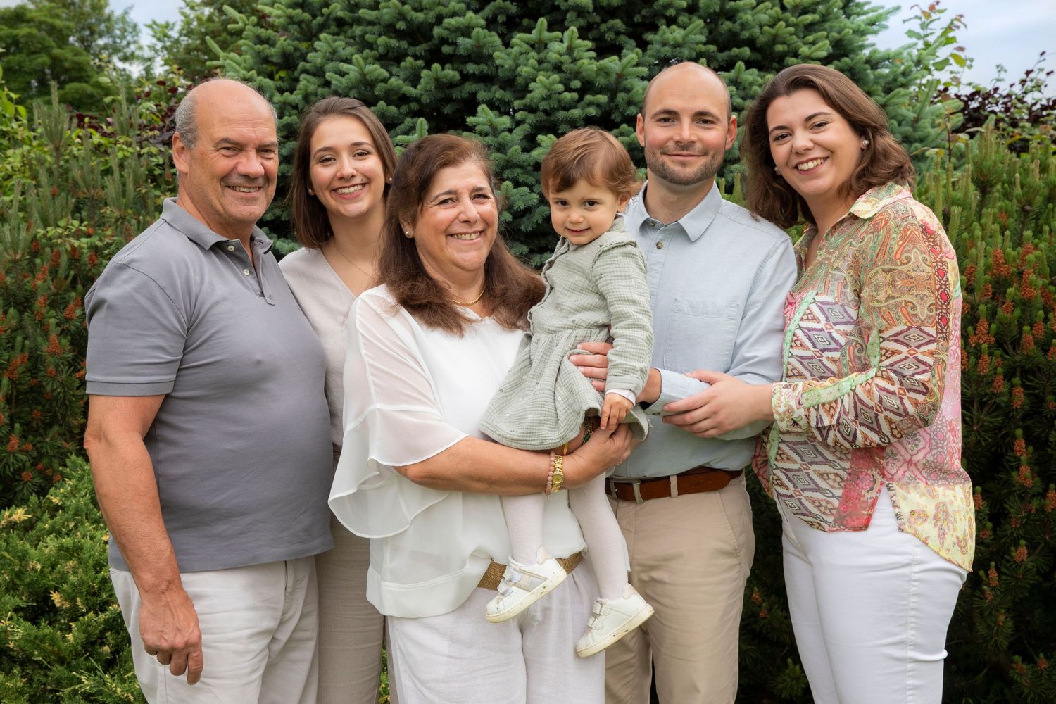 Multi-generational family gathering outdoors wearing coordinated white and neutral clothing.