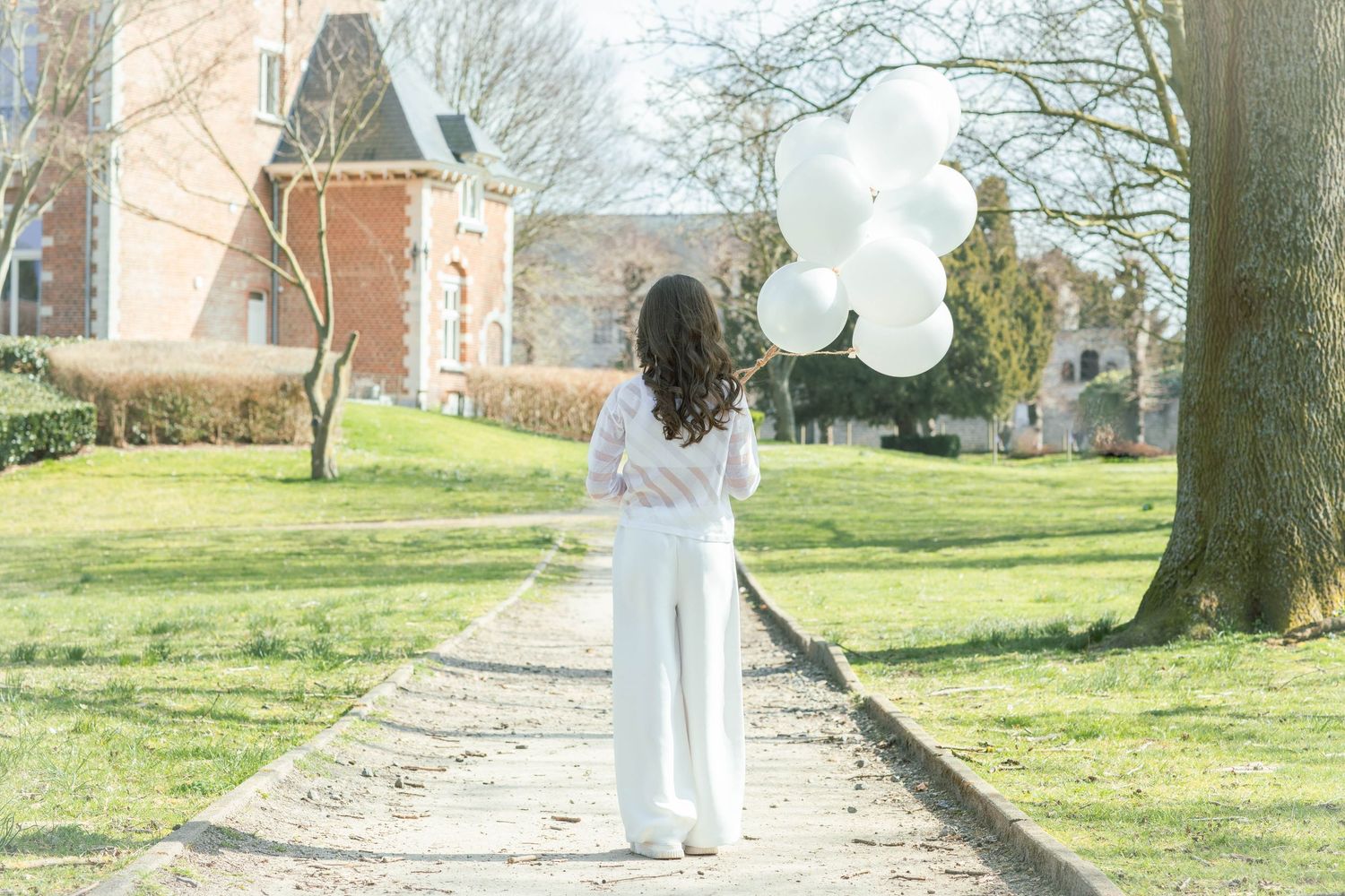 A row of white balloons line a path leading to a brick church building on a sunny spring day.