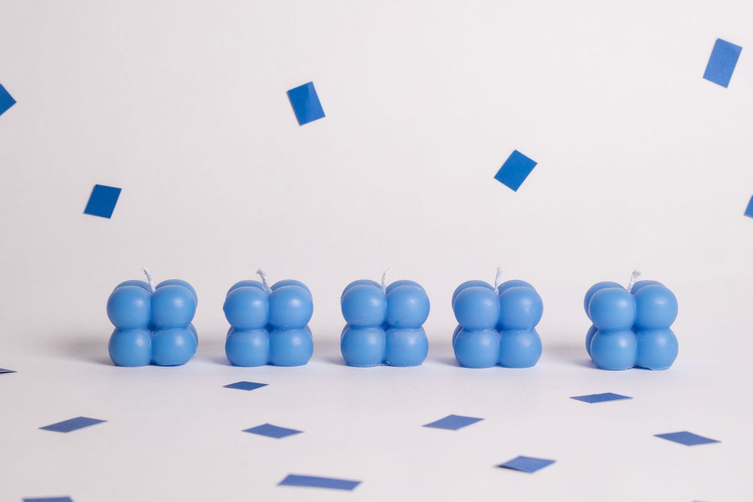Blue rubber ducks lined up in a row on a white surface with scattered blue confetti.