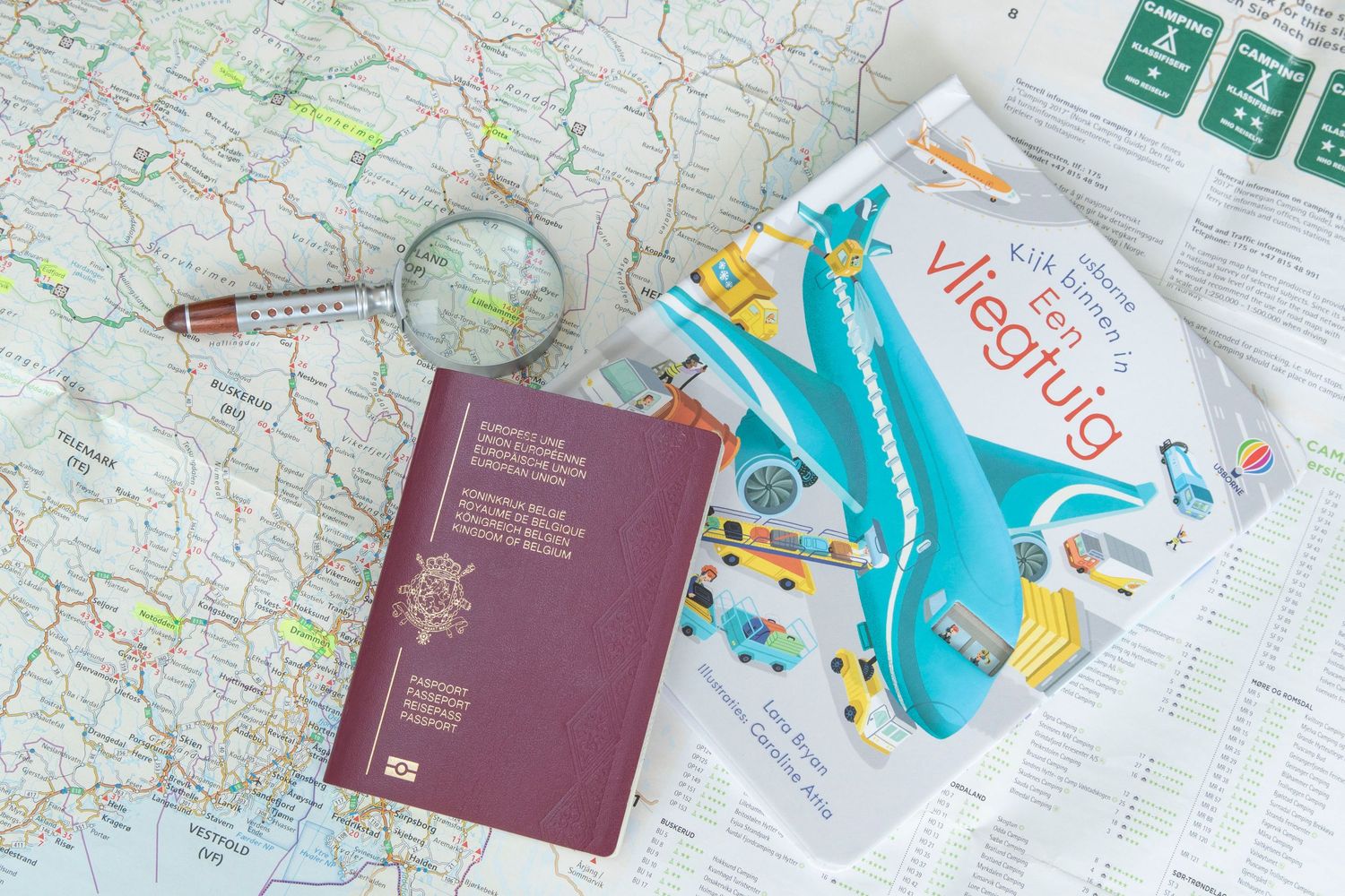 Travel planning setup with passport, map, and airplane toy on white surface.