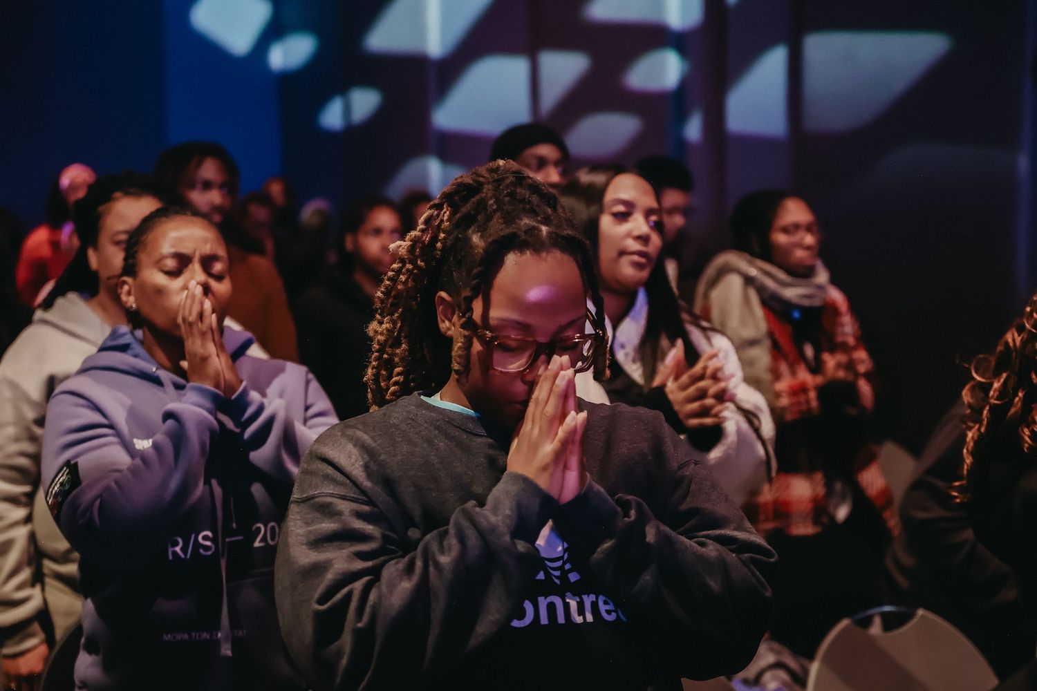 A group of people singing and worshipping together during an emotional church service.
