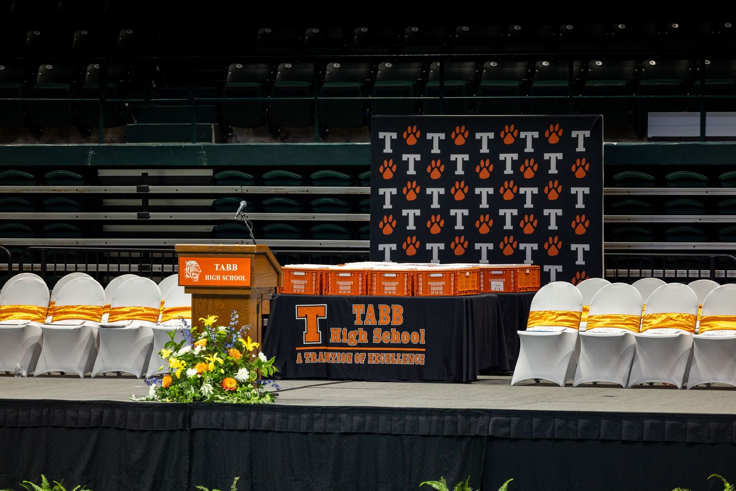 Tabb High School graduation ceremony stage setup with orange and white decorations, podium, and tiger logo backdrop.