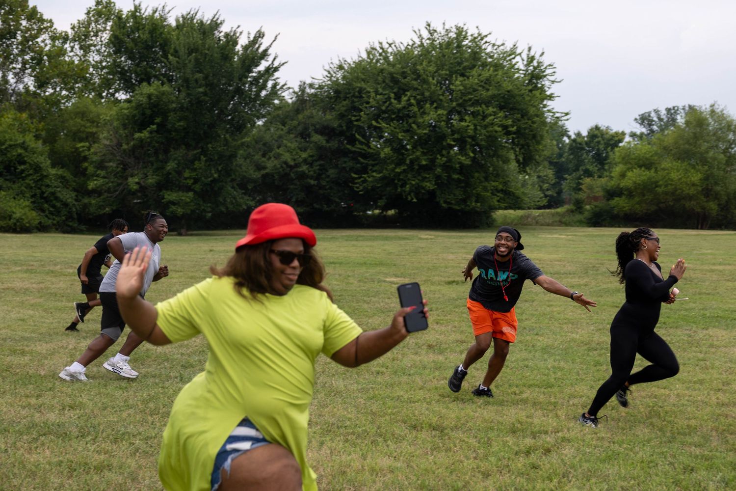 Group of people playing outdoor games in a green park field on a summer day, laughing and running together.