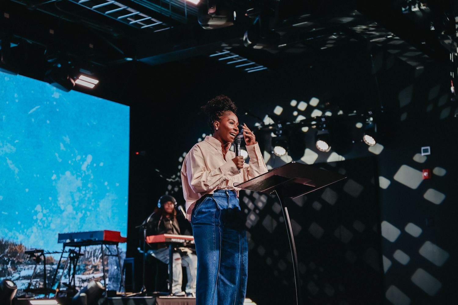 Musicians perform on stage with guitars and microphones at a live concert with blue lighting effects.
