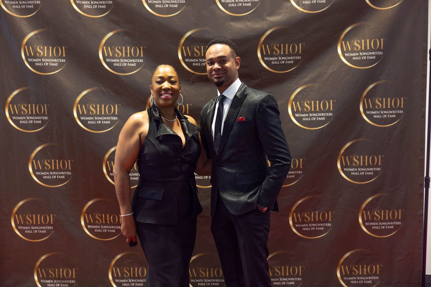 A man and woman pose together at a WSHOI event backdrop wearing formal attire.