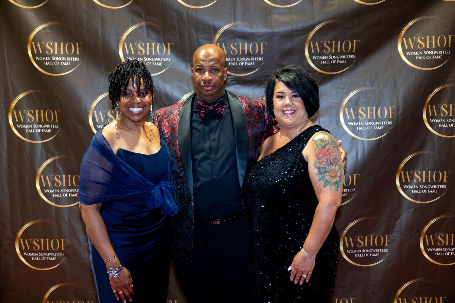 Three people pose together smiling at WSHOF Hall of Fame event on gold step-and-repeat backdrop.