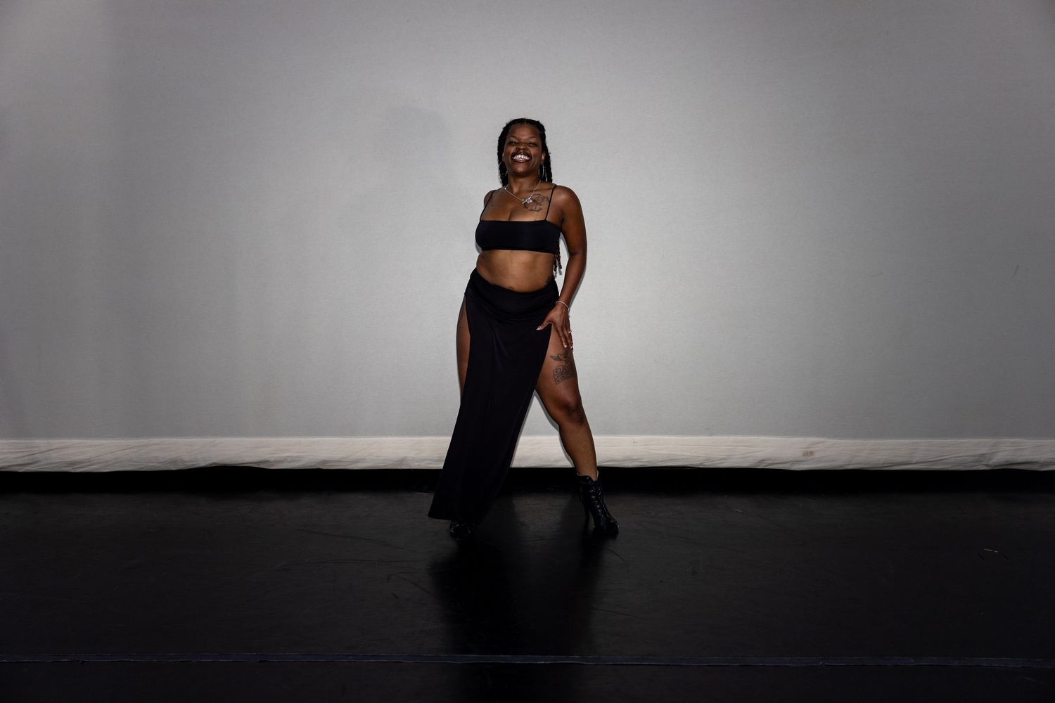 Woman in black crop top and maxi skirt posing dramatically in a dance studio.