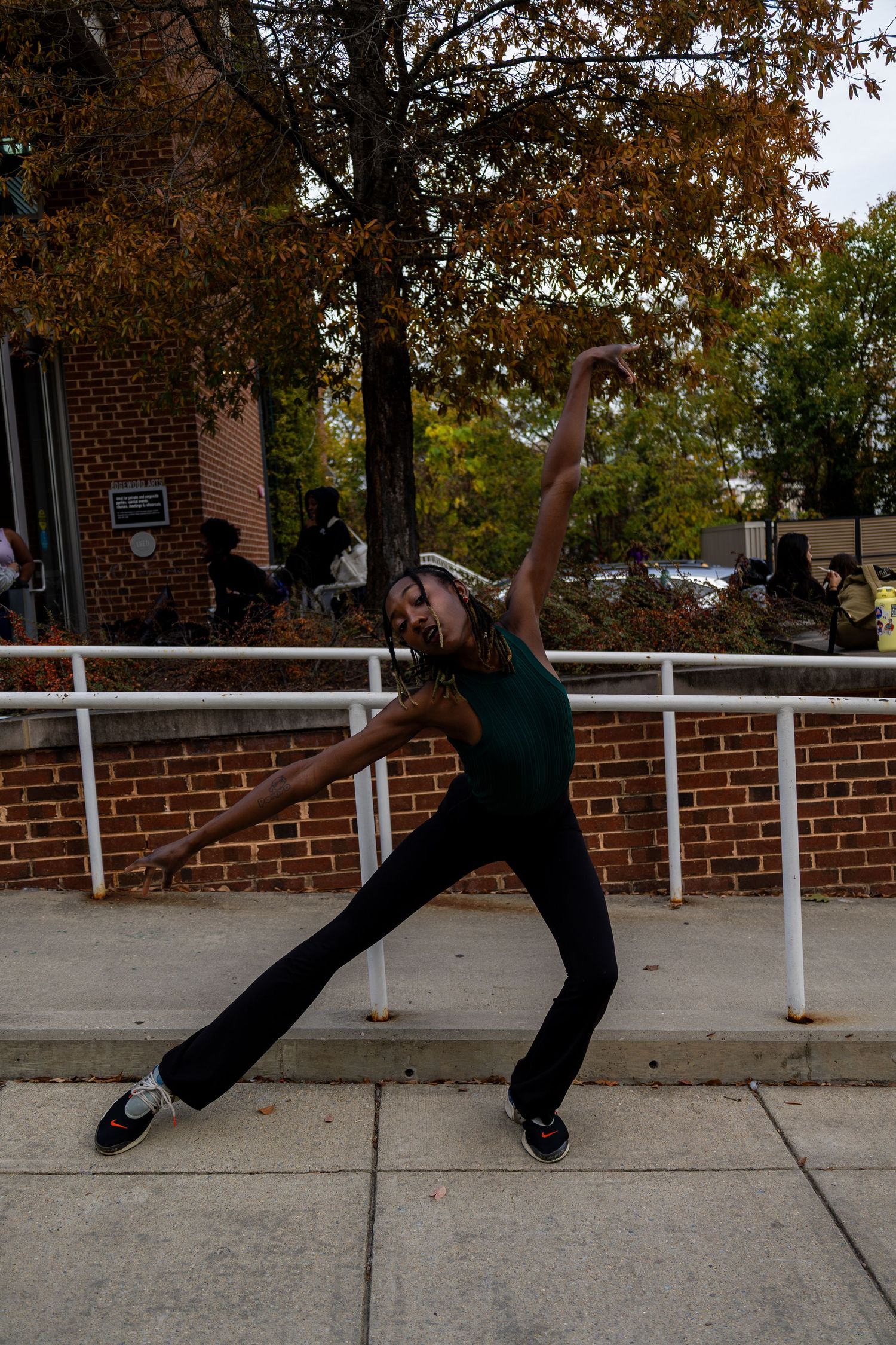 Person in dark clothing performs dramatic floor pose near brick wall.