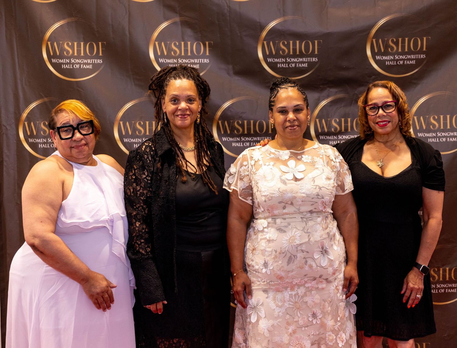 Four women posing together at the WSHOF Women Songwriters Hall of Fame event backdrop.