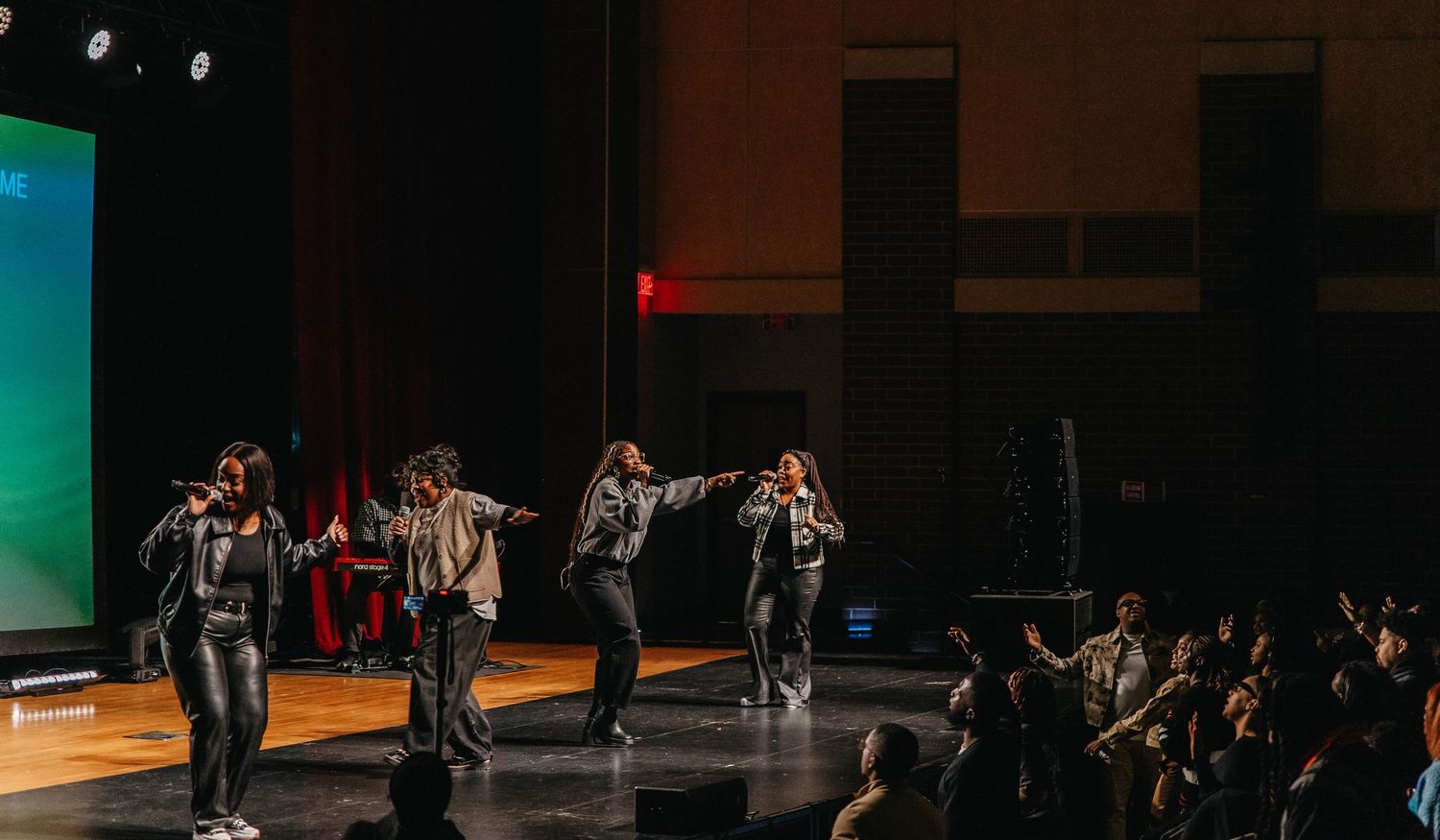 A dark stage performance with dancers in silhouette striking dramatic poses against colorful lighting effects.