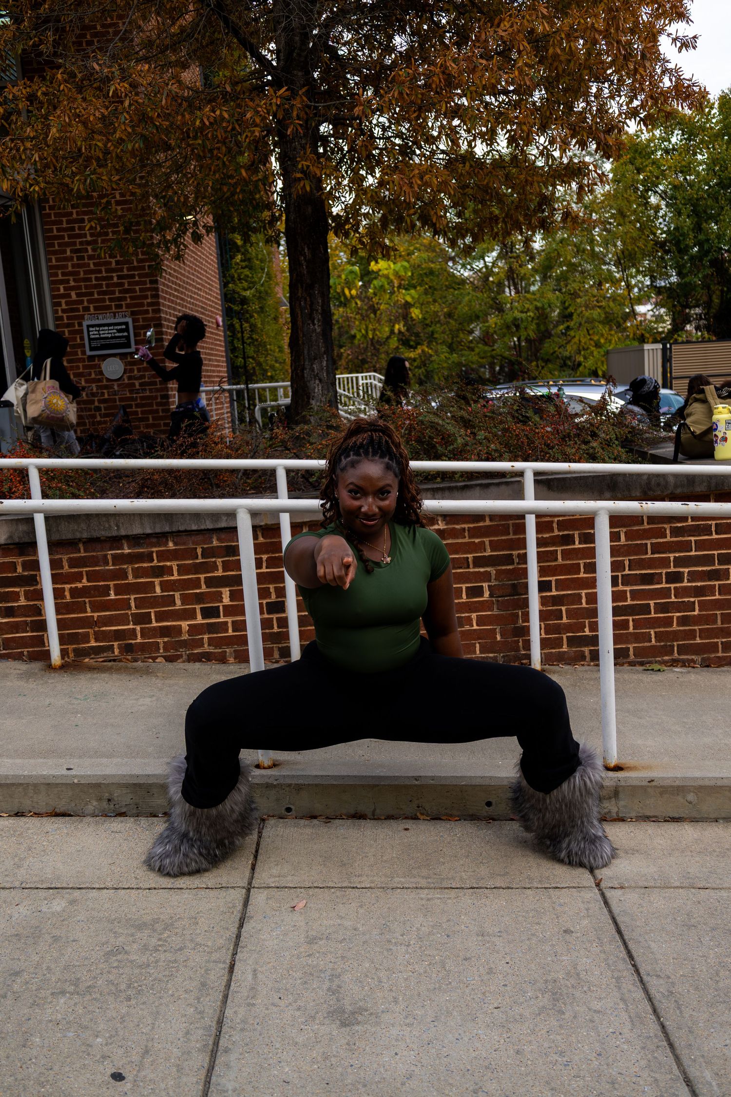 Person in green top performs split pose on concrete near white railing.