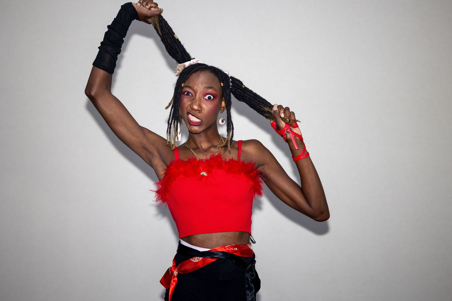 Woman in red crop top and black shorts poses dynamically against white background.