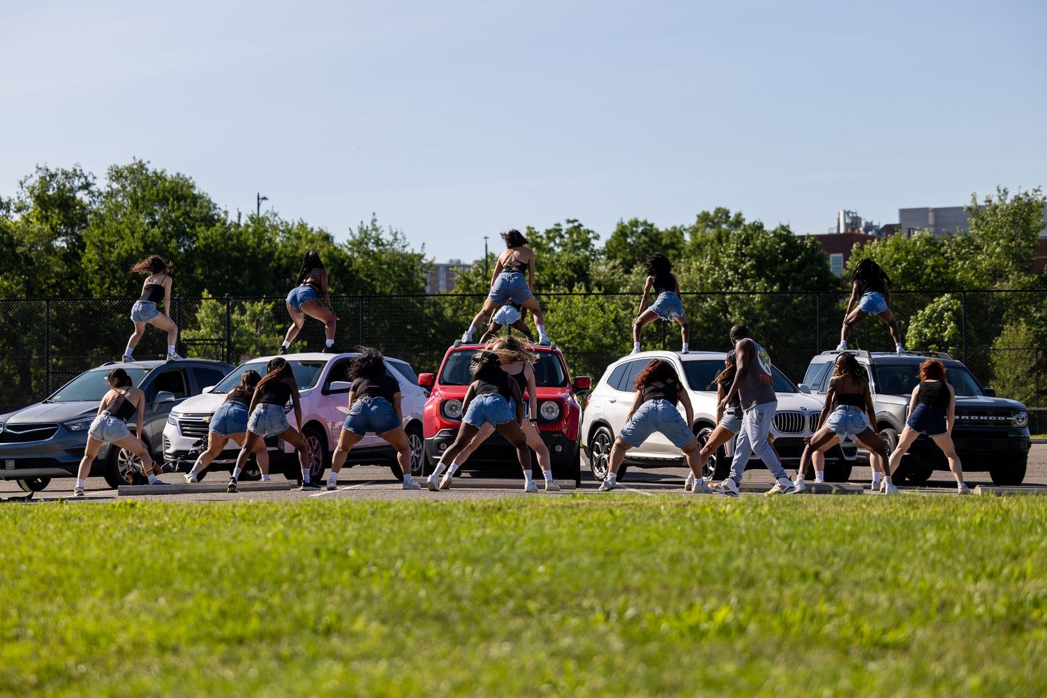 A group of cheerleaders performing a synchronized routine in a parking lot on a sunny day.