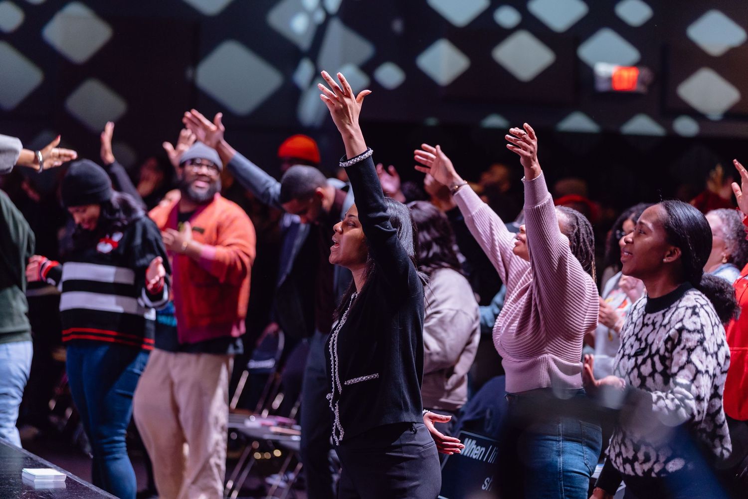 A crowd of people dancing with raised arms at a lively indoor event or concert venue.