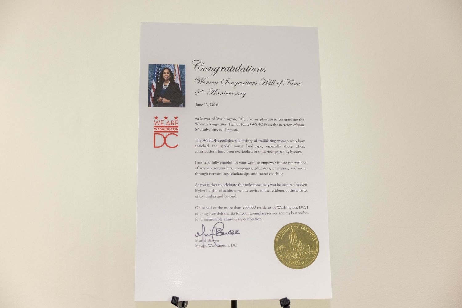 Framed congratulatory certificate on easel with gold seal, photo, and DC logo for Women's Recognition Hall of Fame.