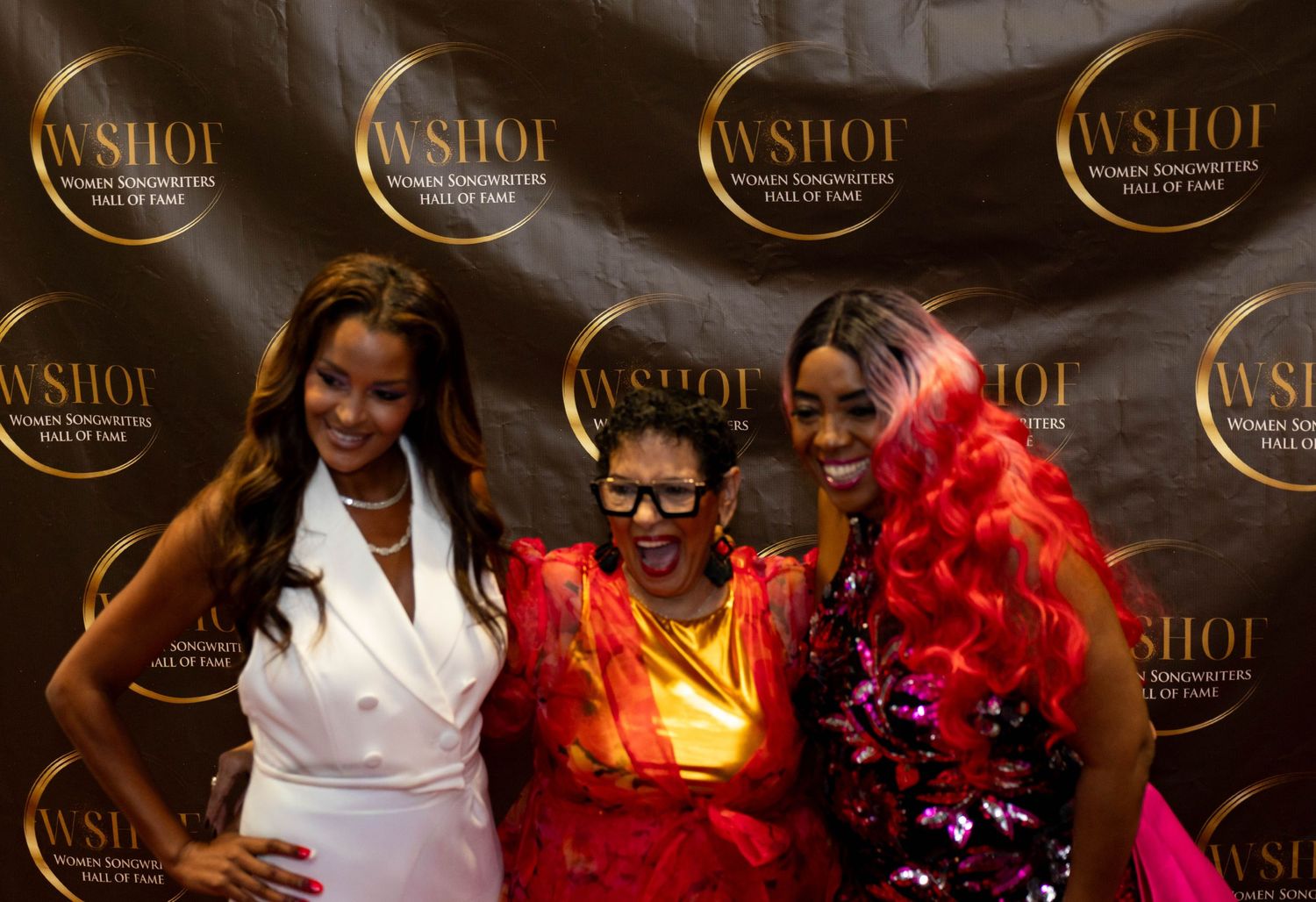 Three women smile together at the WSHOF Women Songwriters Hall of Fame awards ceremony.