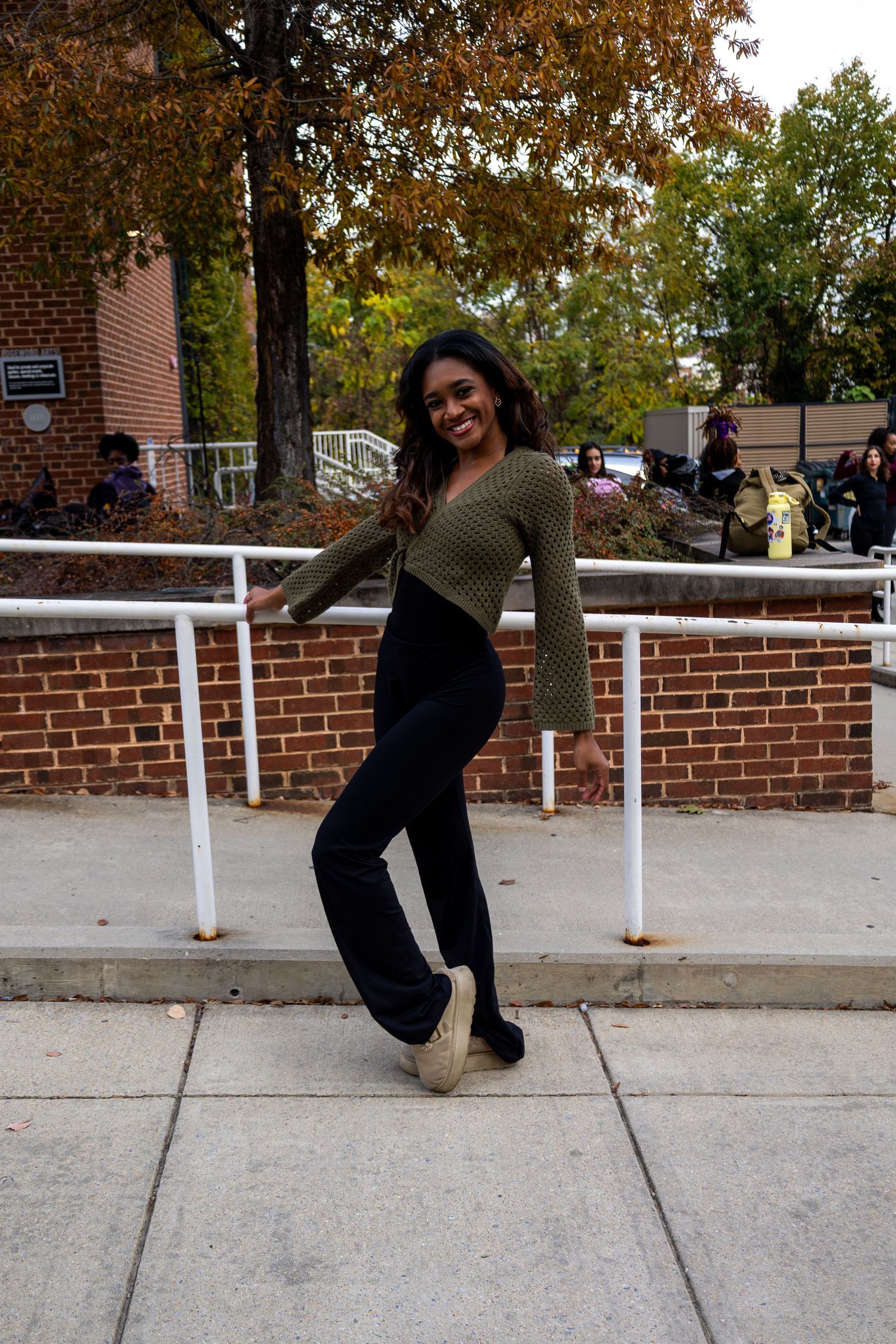 Artistic motion poses photographed against brick wall and white railing in autumn setting.