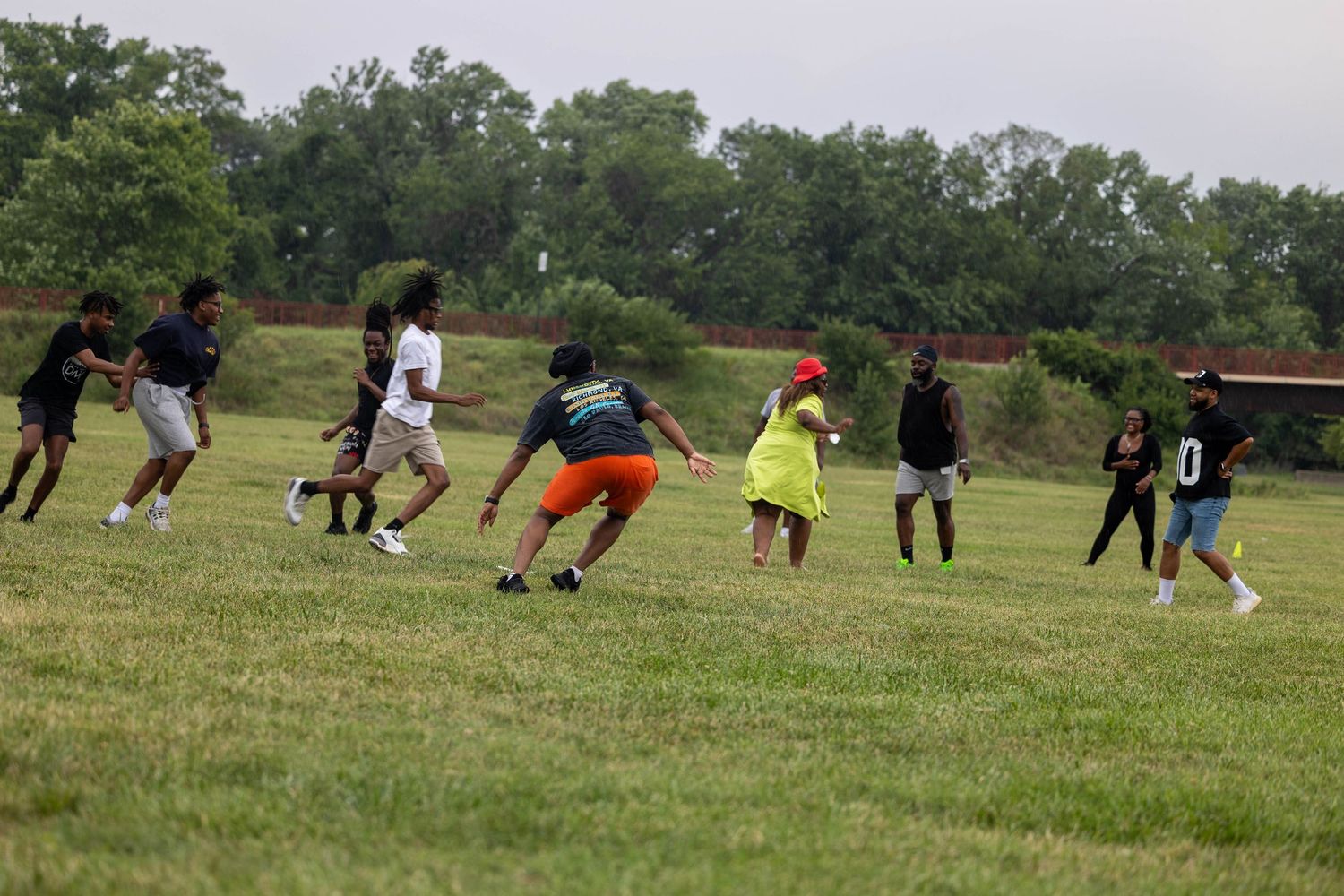 Group of people playing flag football on a grassy field on a cloudy day.