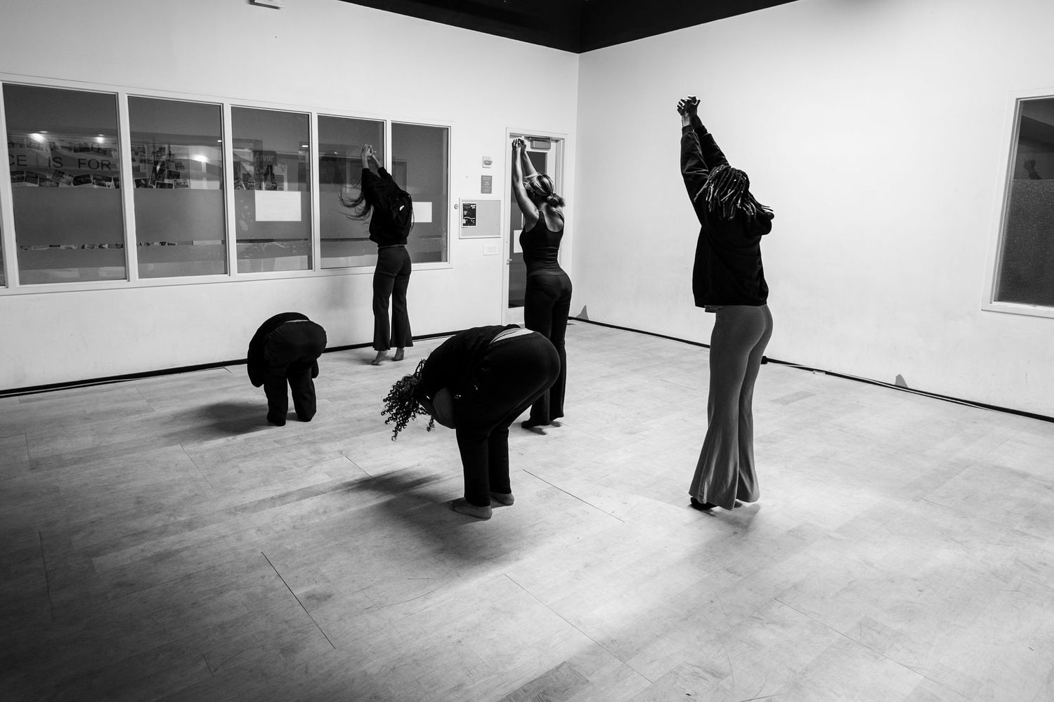 Black and white photo of dancers in various poses during a contemporary performance in a gallery.