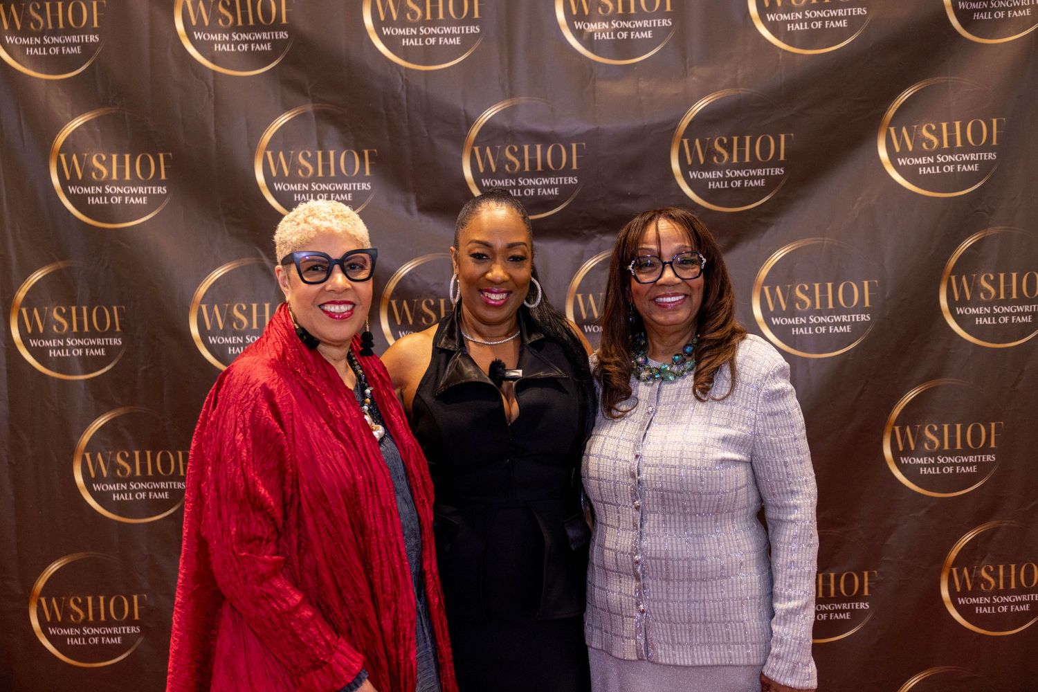 Three women posing together at a WSHOI event backdrop, dressed in elegant attire at a formal celebration.
