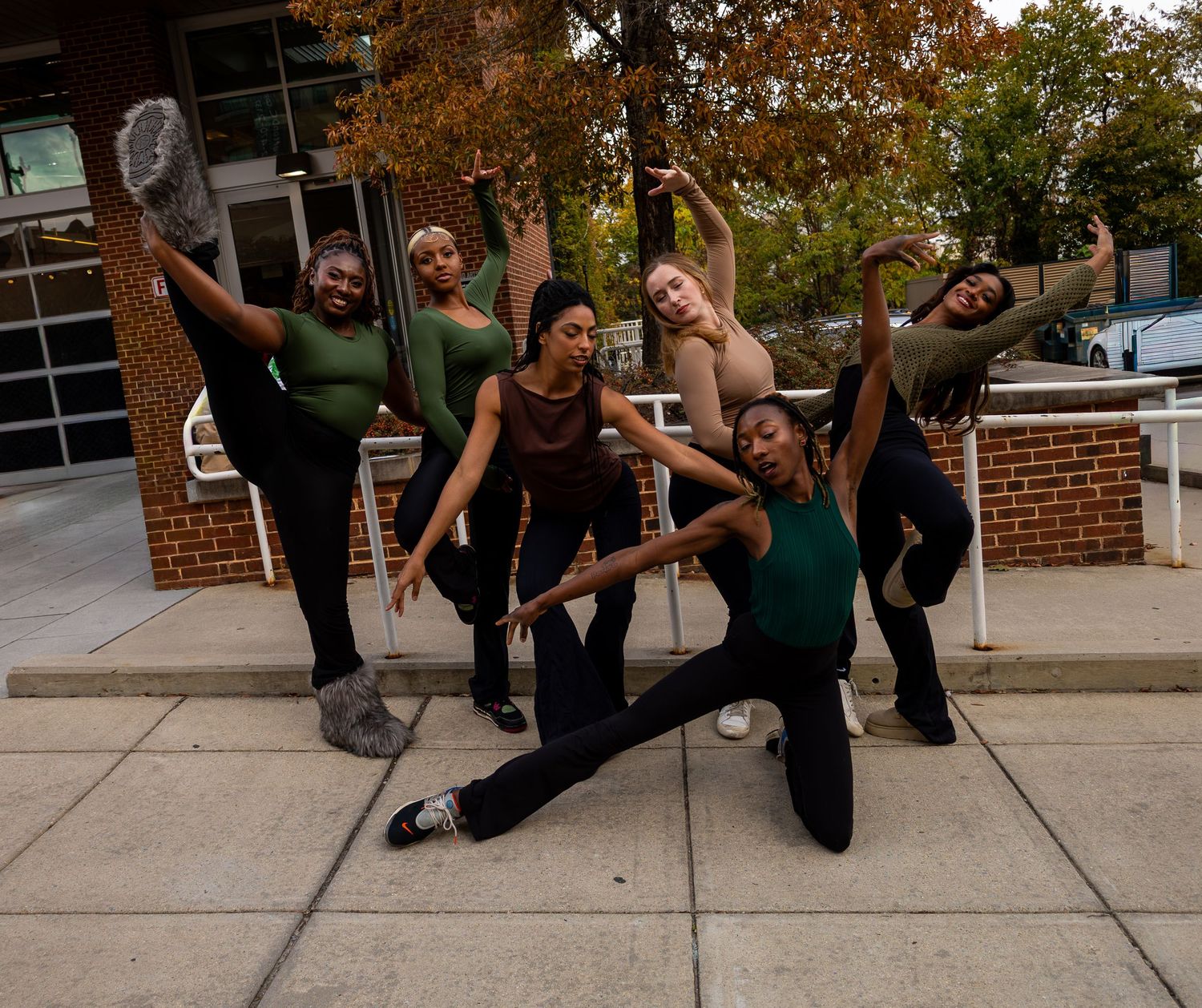 A group of dancers performing synchronized moves on an outdoor sidewalk.