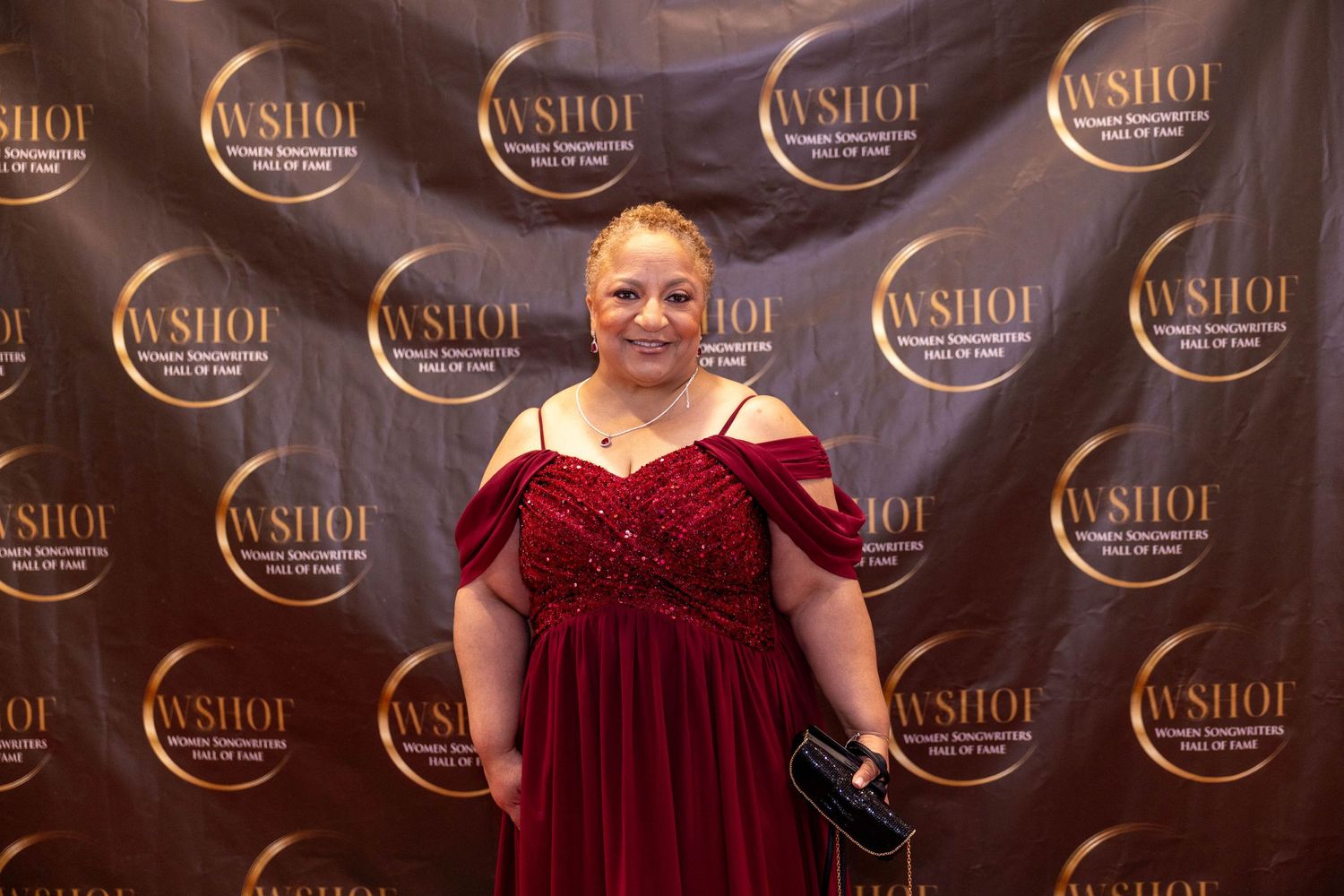 Woman in elegant red gown posing at the WSHOF Women Songwriters Hall of Fame event.