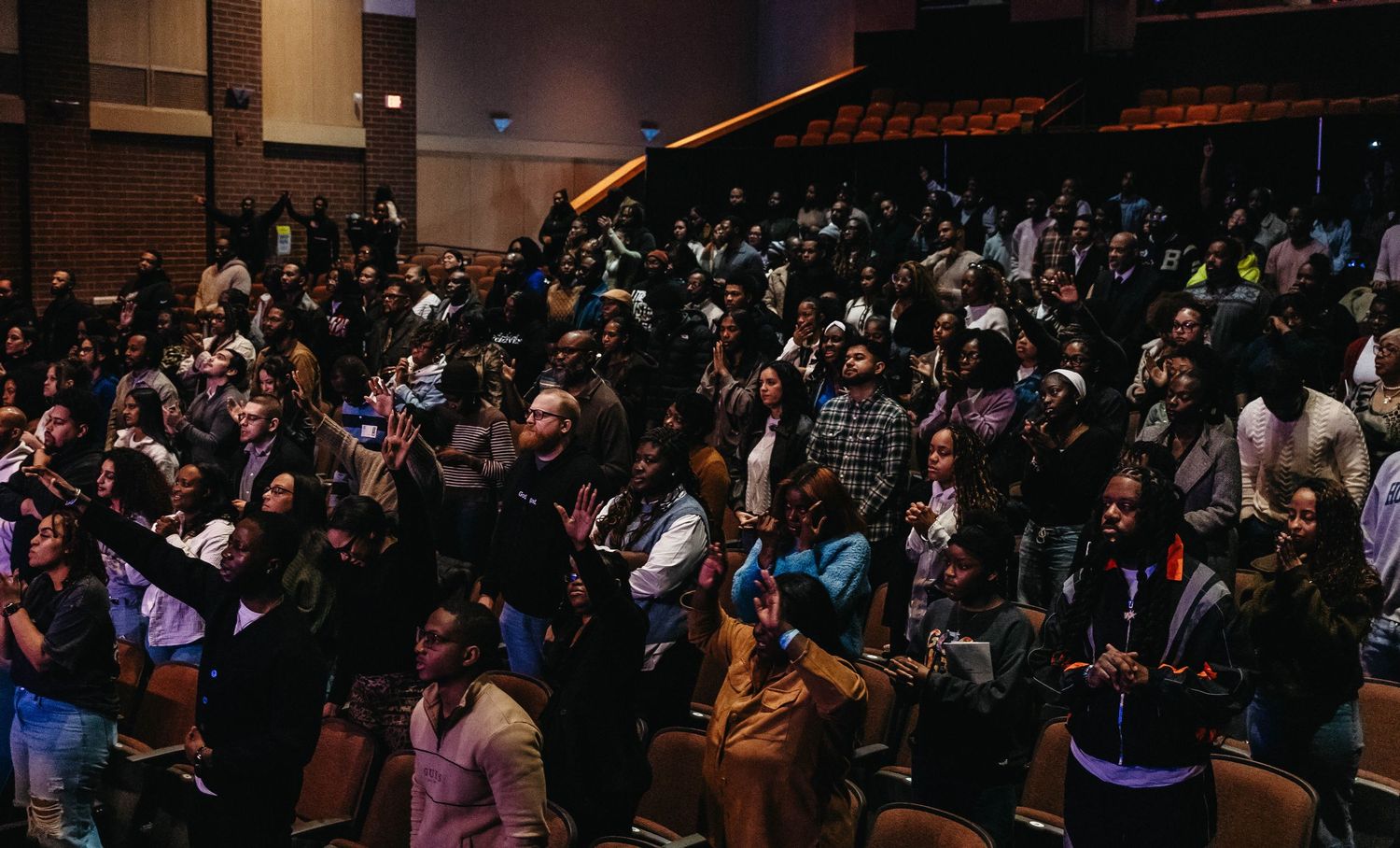 A large crowd of concert attendees fills a dark indoor venue during a live performance.
