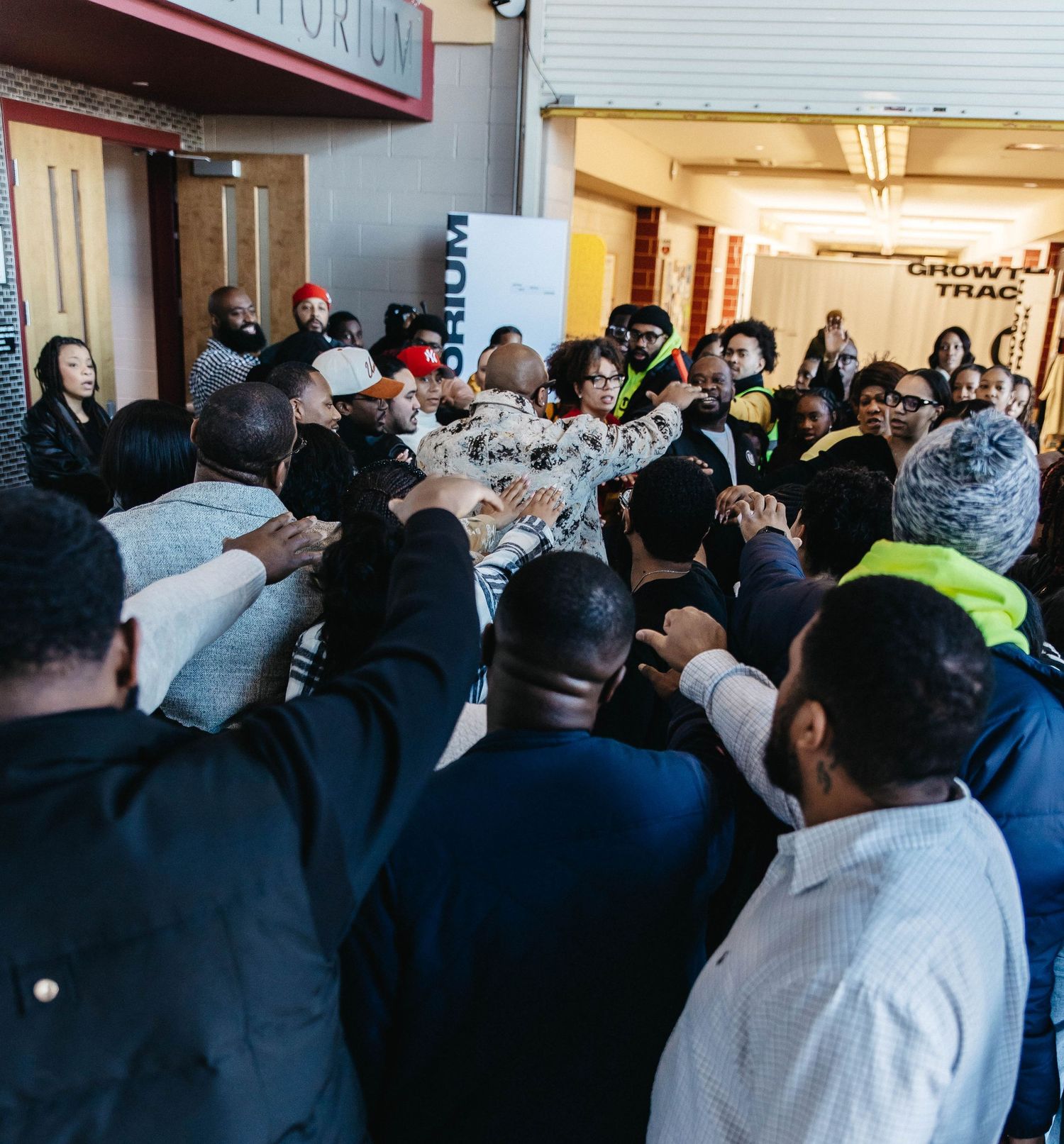 Large crowd of people gathered tightly at a retail entrance during a busy shopping event or sale.