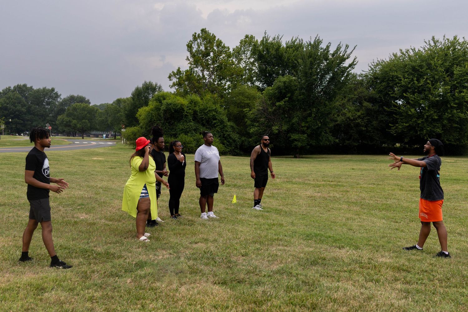 Group of people participating in an outdoor sports activity drill in a park on a summer day.