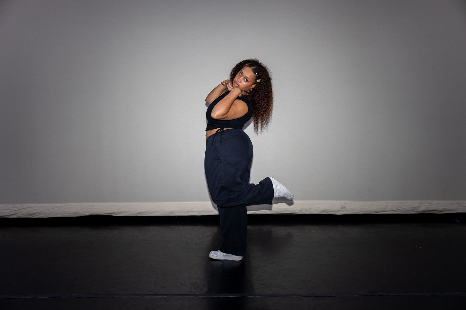 Female dancer in navy wide-leg pants striking a dynamic hip-hop pose in a dance studio.