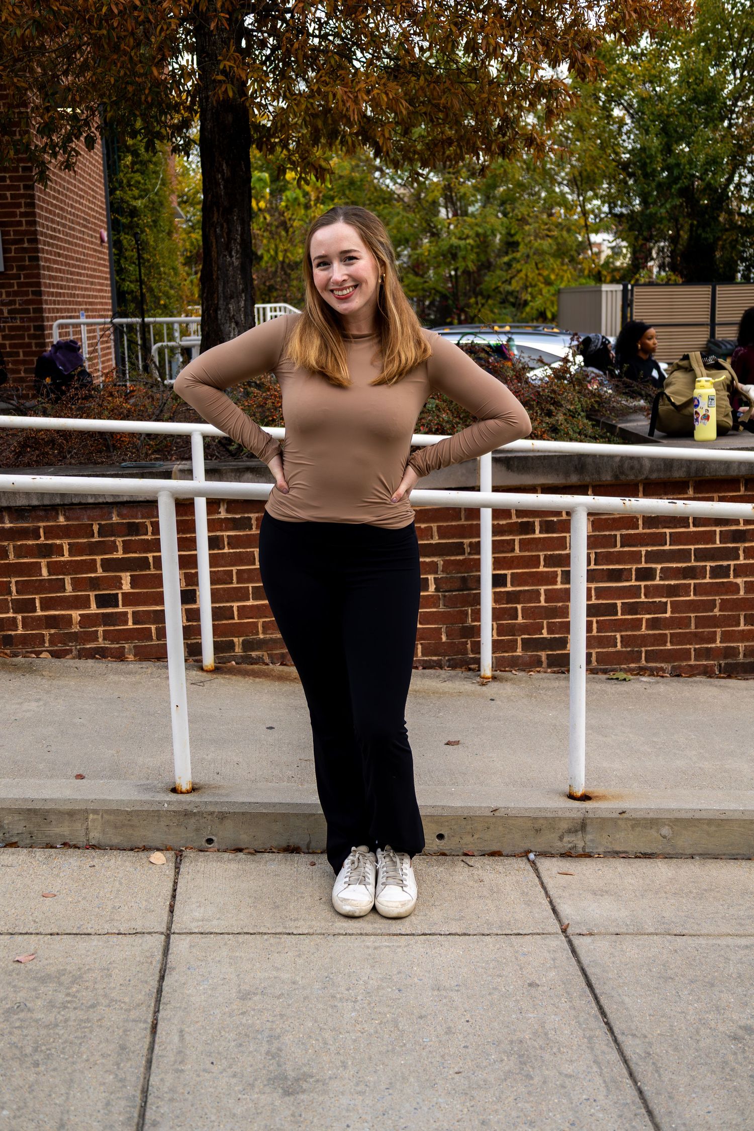 Playful poses captured in sequence against brick wall and white railing outdoors.