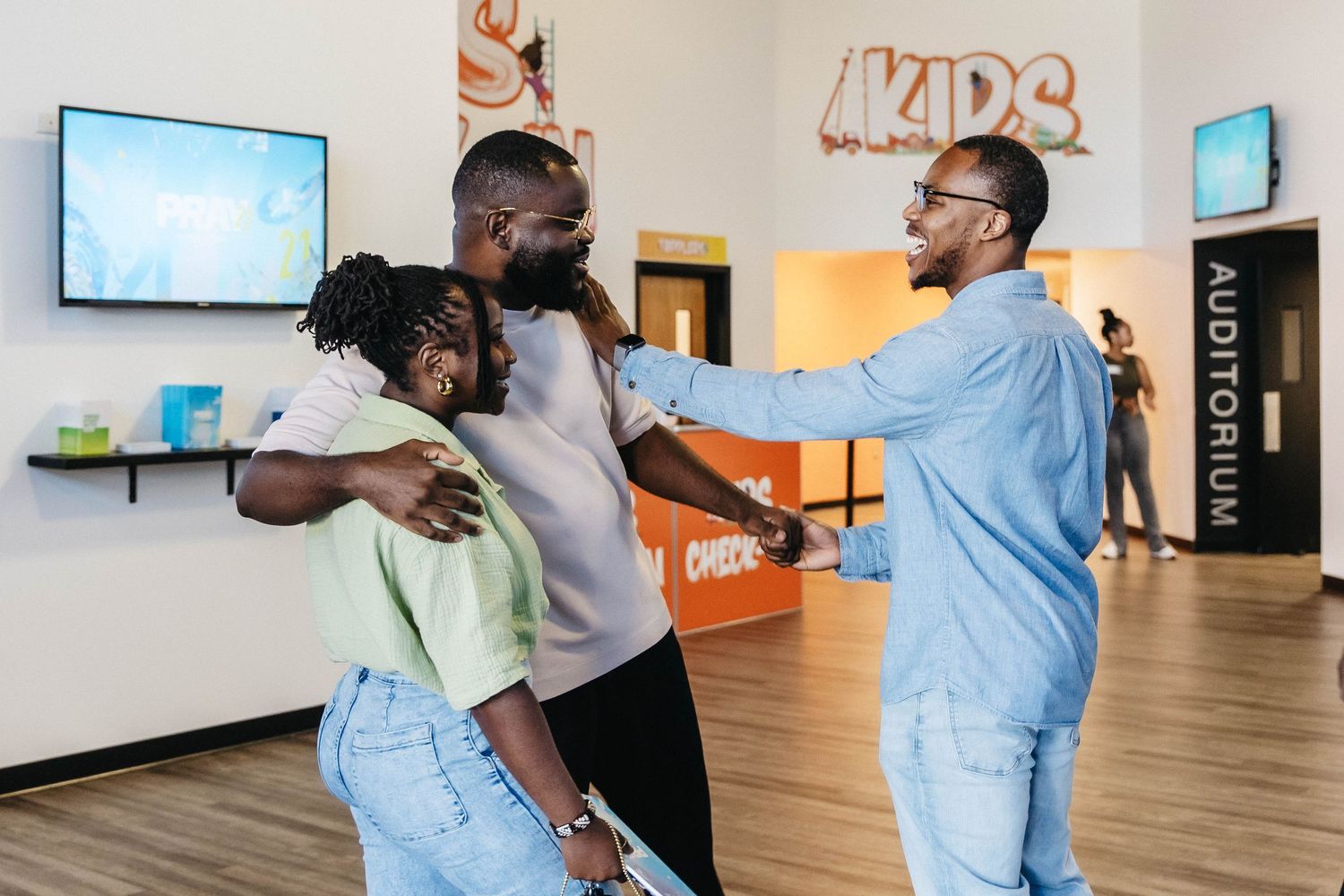 People sharing a joyful moment together in a modern indoor space with TV screens.