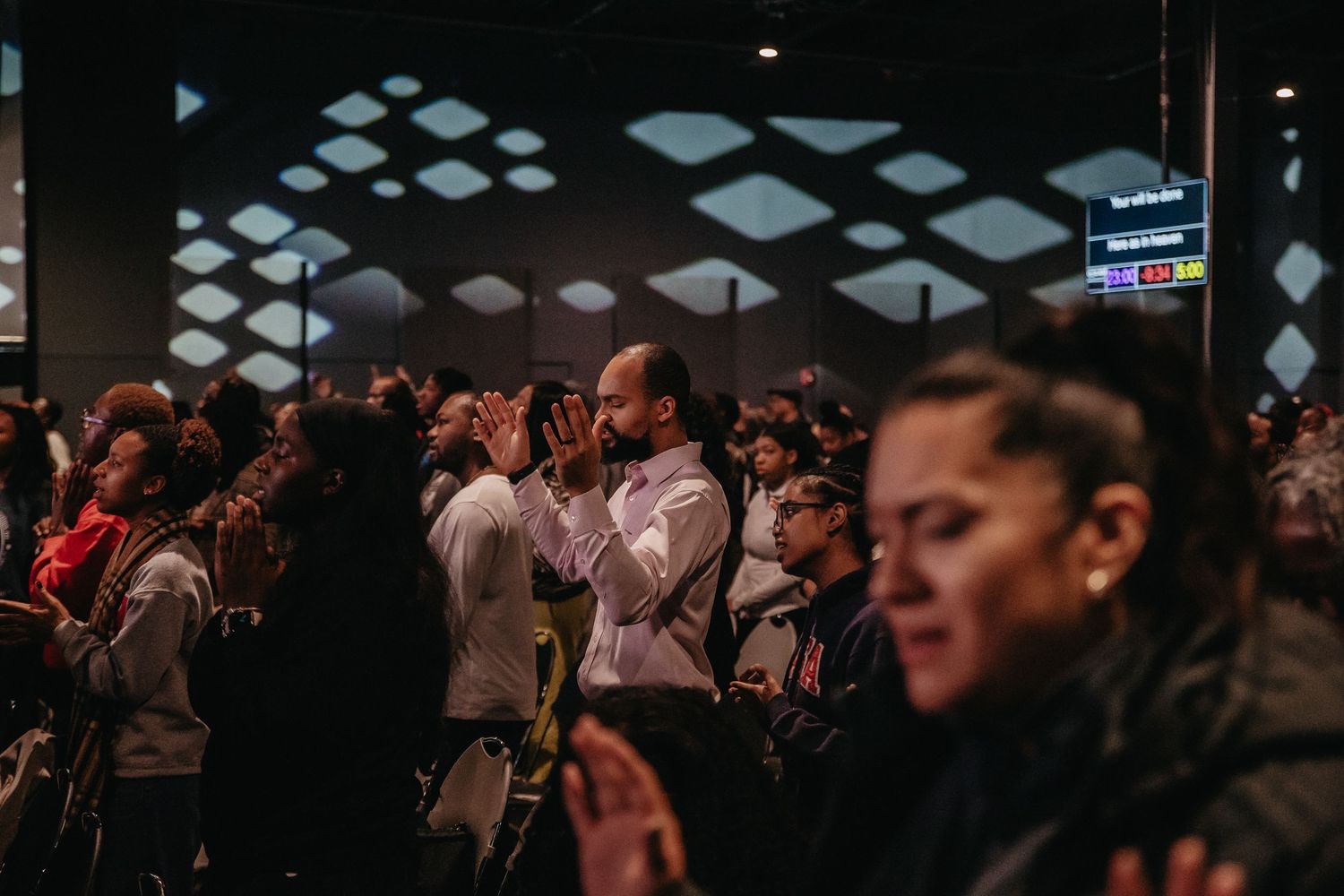 A dark concert venue filled with audience members watching a performance on stage.