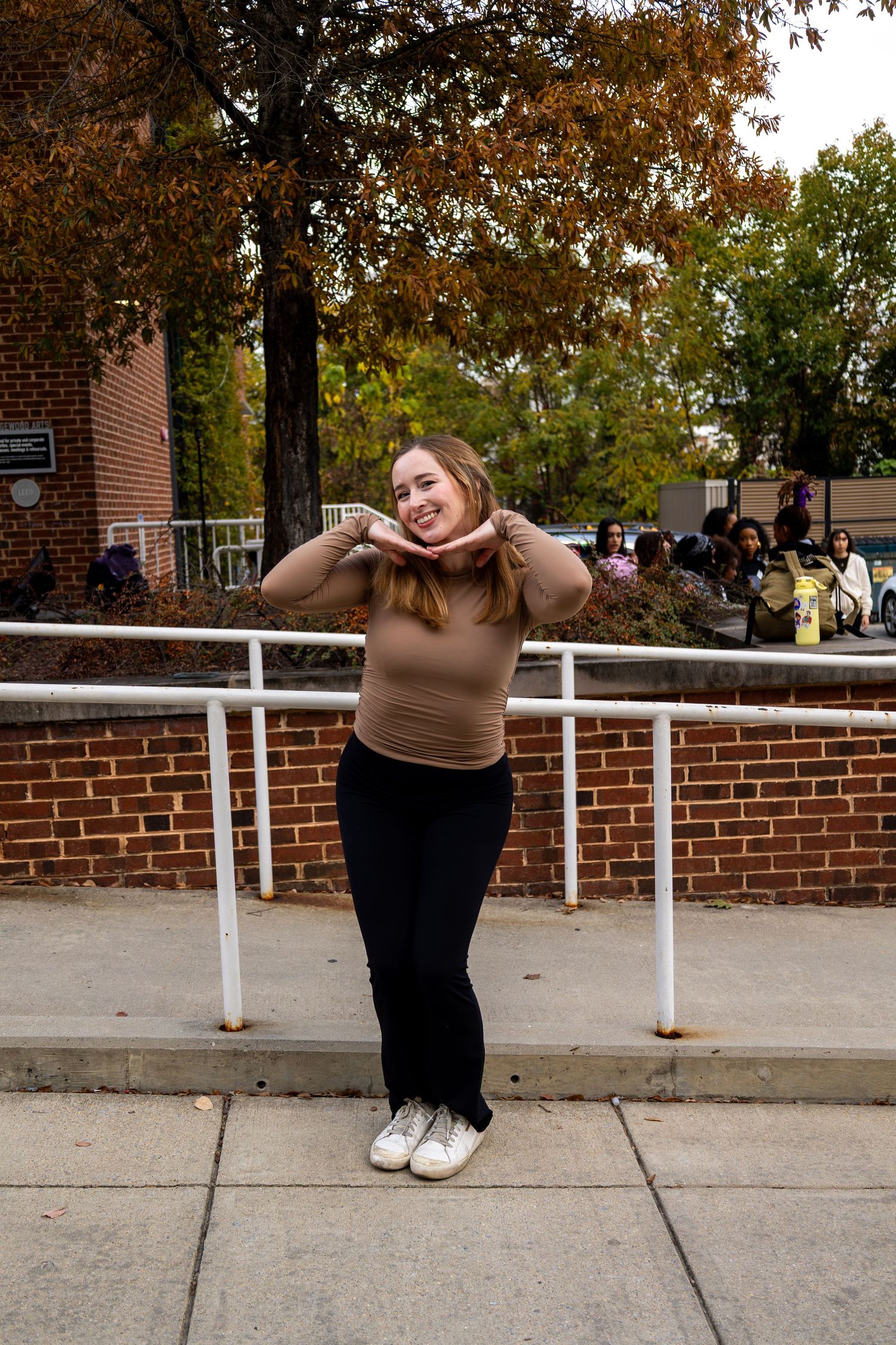 Expressive poses showcased against autumn backdrop with white railing and brick wall.