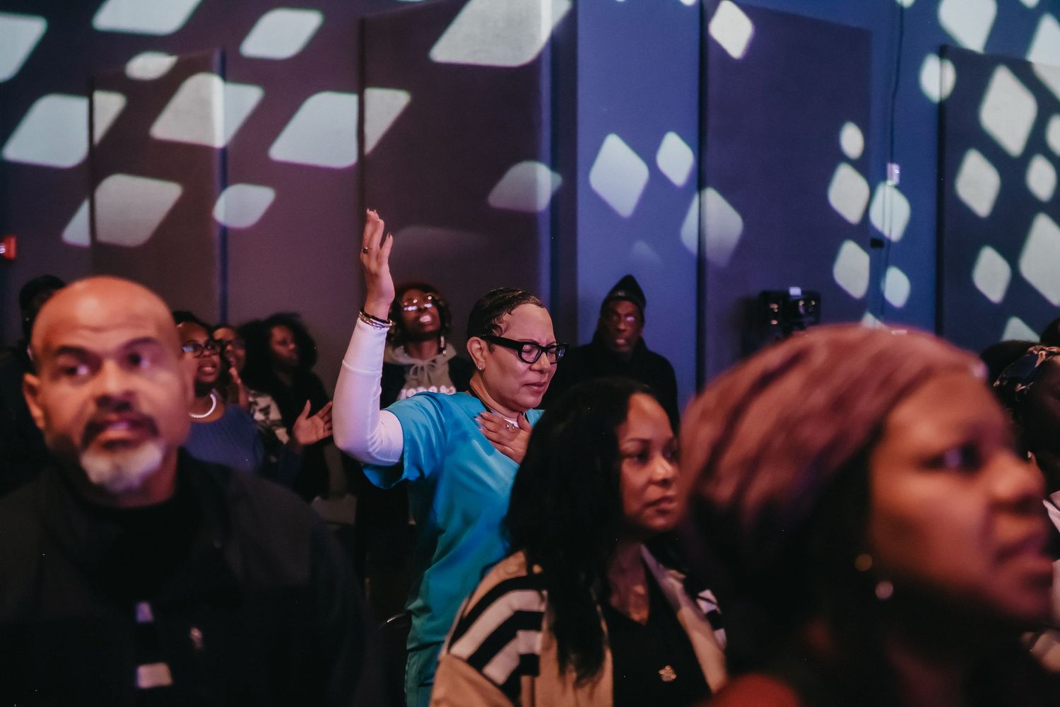 A diverse crowd of people cheering and dancing at a lively indoor event or concert.