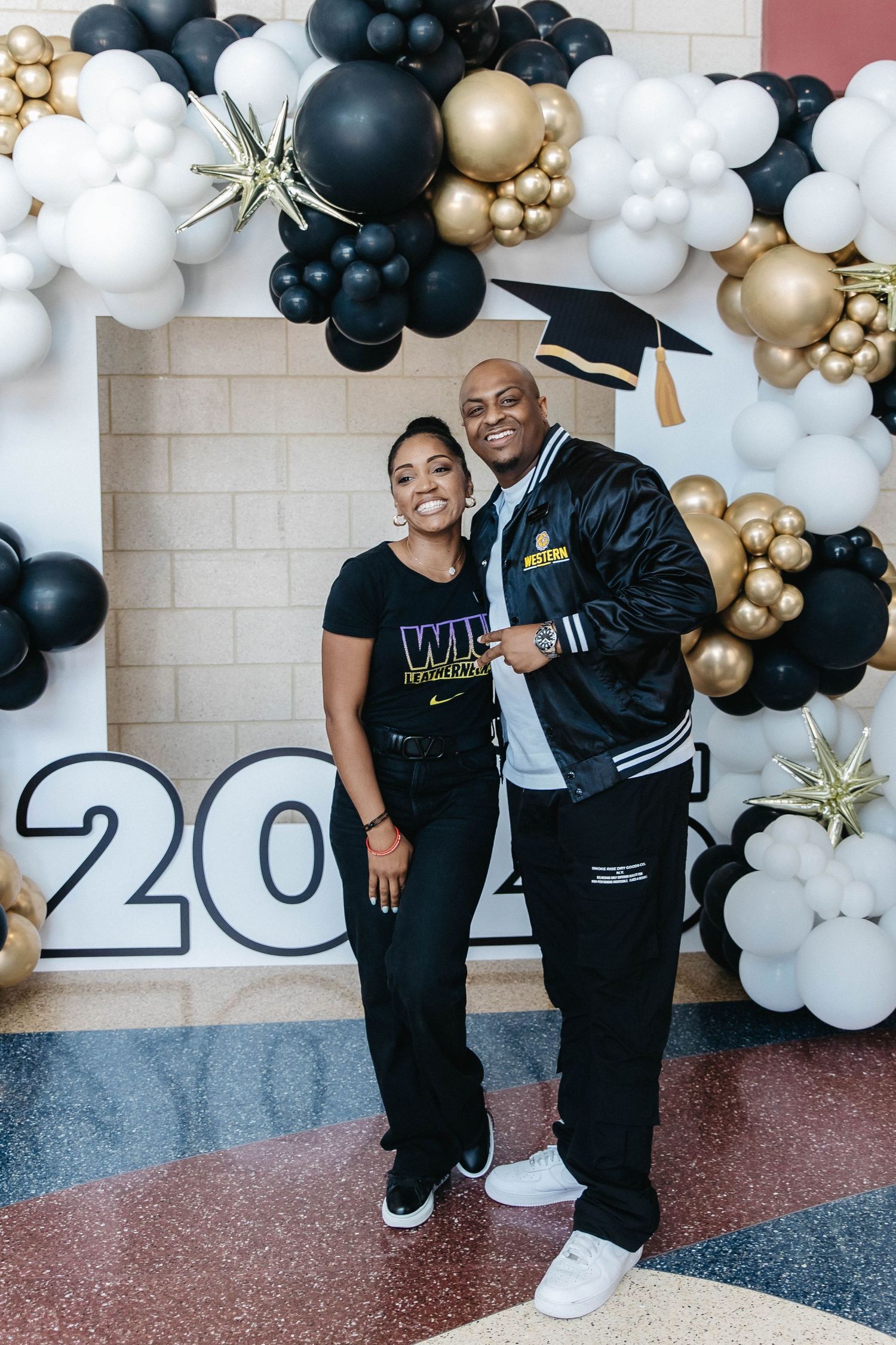 Graduation celebration setup with black, gold and white balloon arch and 2023 numbers.