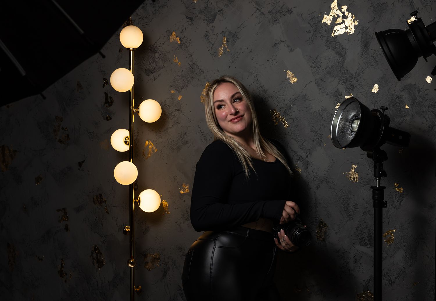 A moody photoshoot setup with round pendant lights and dark wallpaper creates a dramatic atmosphere.