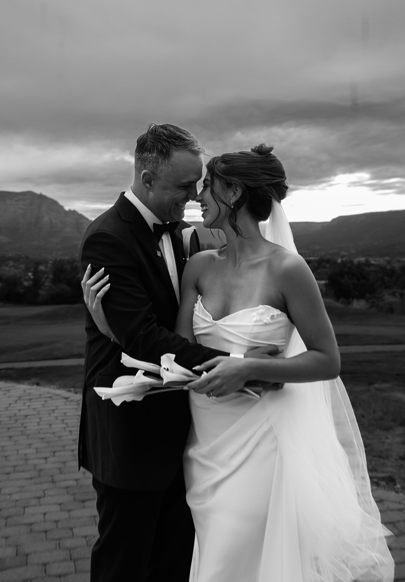 A romantic black and white wedding photo of a couple embracing outdoors with mountains in the background. Sedona wedding Sedona arizona
