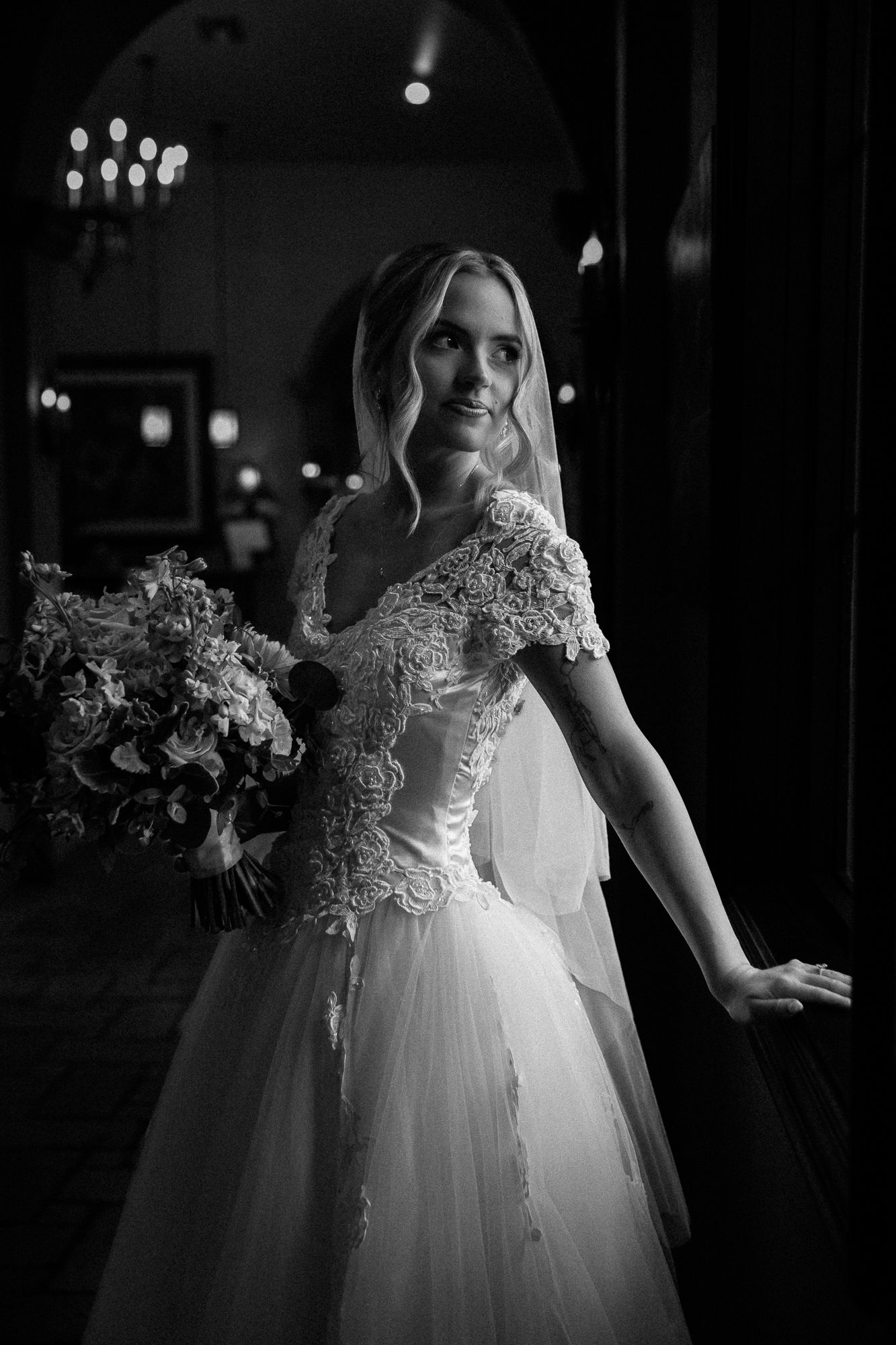 Black and white wedding photos showing bride in flowing tulle gown with lace details and floral bouquet.