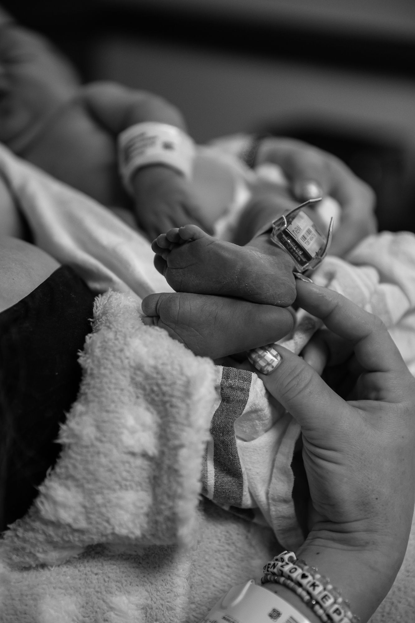 Close-up black and white photo of hands performing a manicure treatment on fingernails.