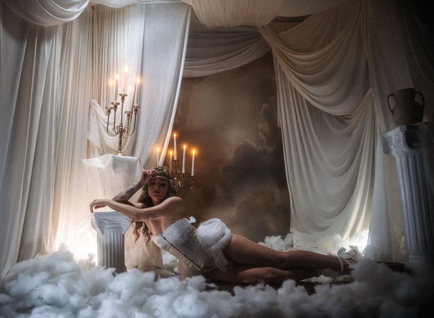 Ethereal bedroom scene with white drapes, candlelight, and cloud-like cotton creating a dreamy atmosphere.
