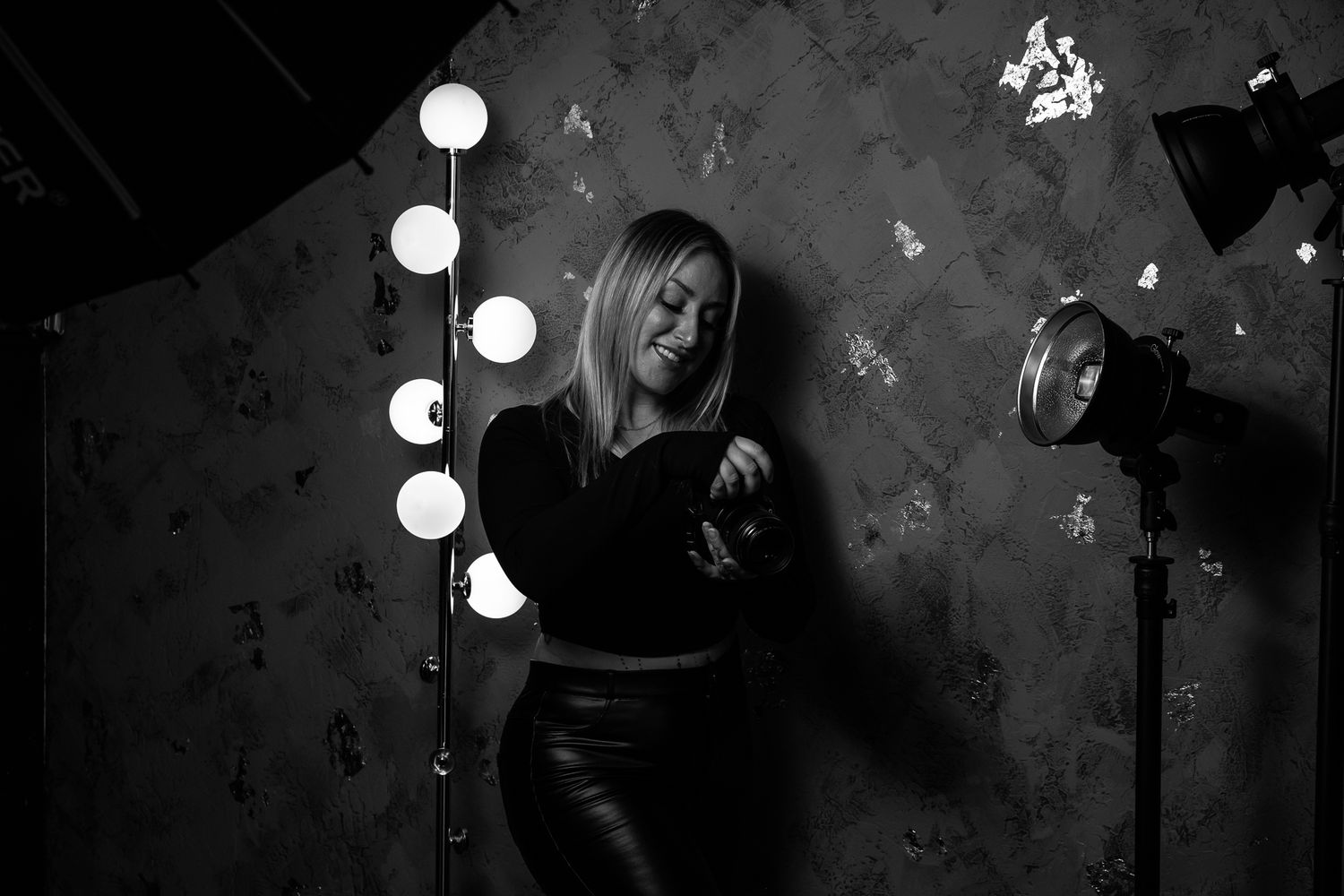 A dramatic black and white studio portrait with vanity lighting and textured background.