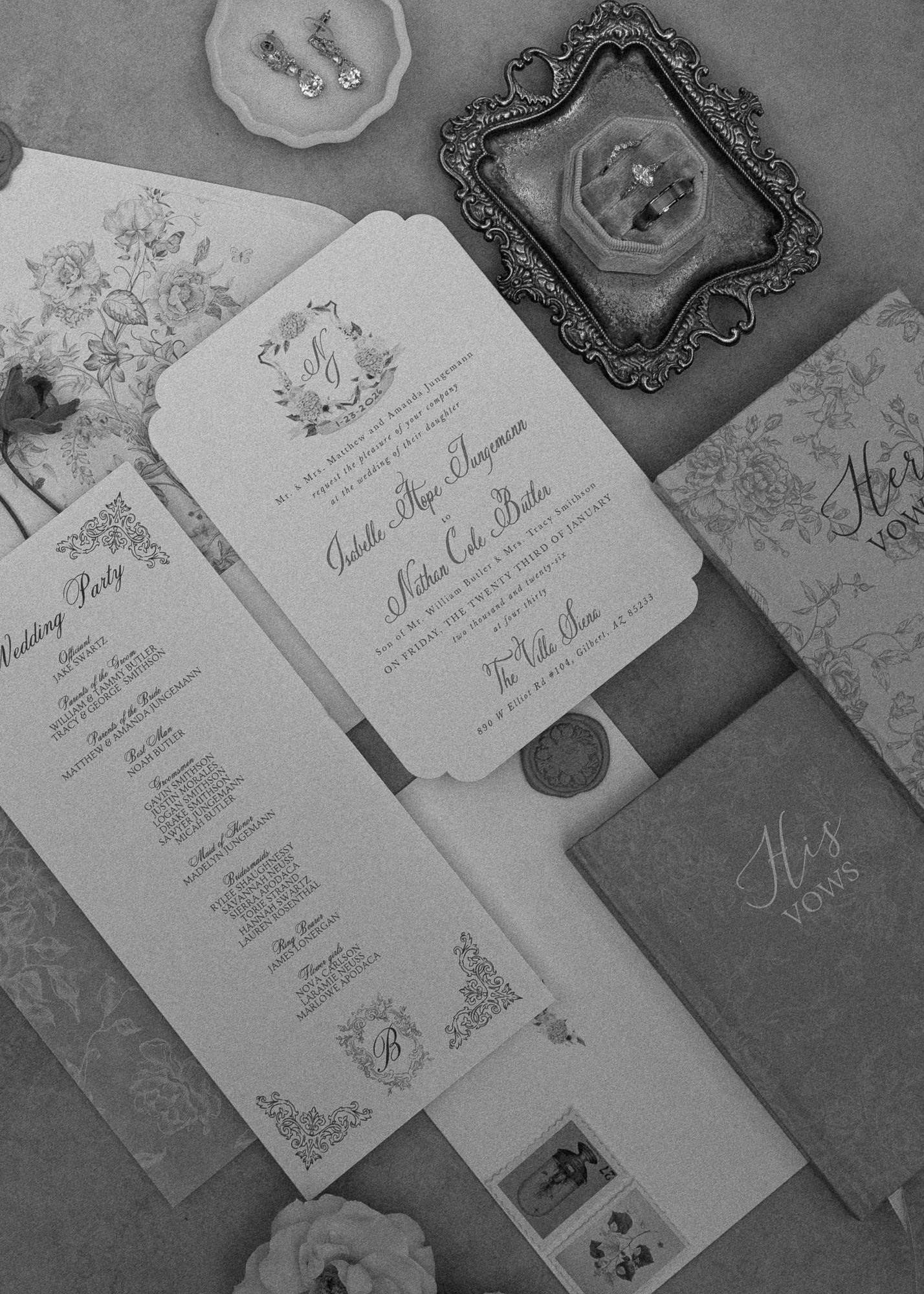 Elegant wedding invitation suite with ornate details and floral designs displayed in black and white.